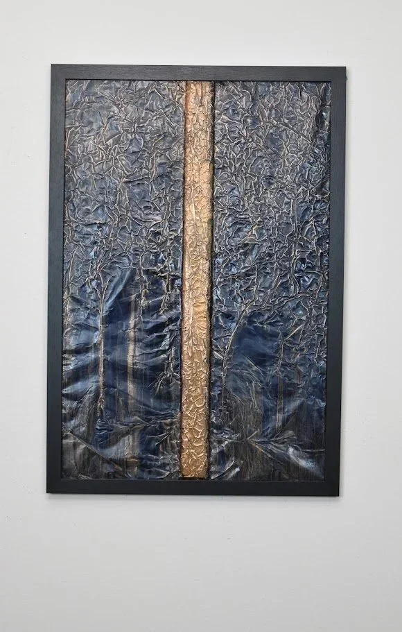 A golden vertical band divides a deep blue metallic field. Displayed framed on a white wall.