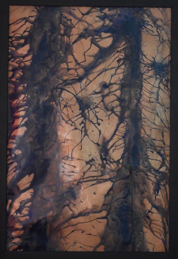 Branching blue currents spread across a warm copper field. Shown close up in a black frame.
