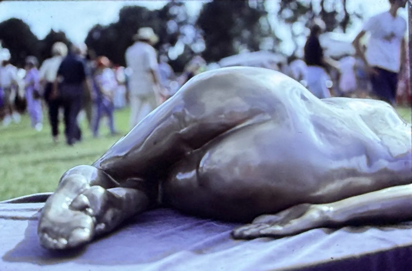 Close-up of the reclining bronze form from the feet upward, highlighting smooth modeling and naturalistic anatomy.