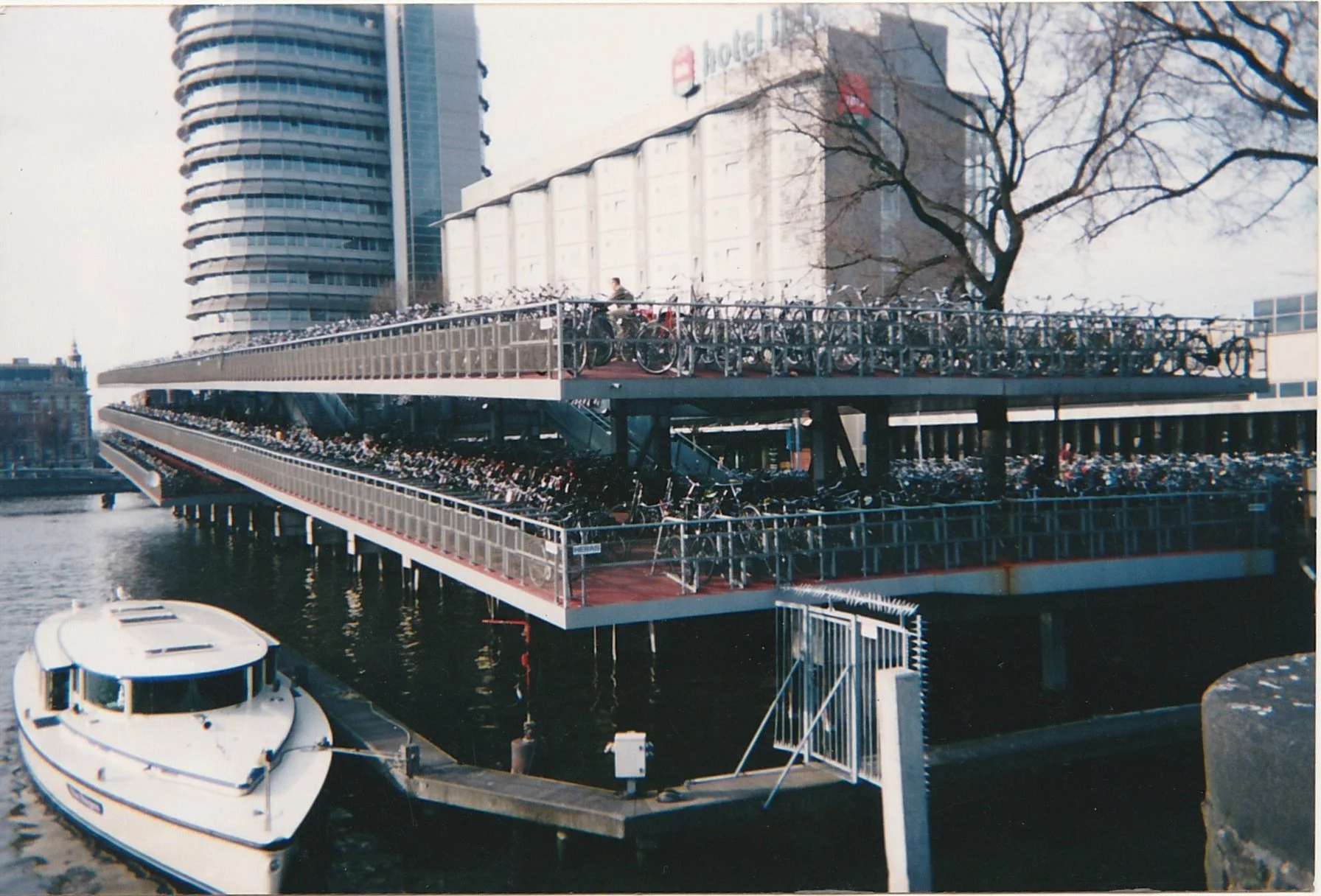Multi-level bicycle parking structure crowded with hundreds of bicycles beside a canal.