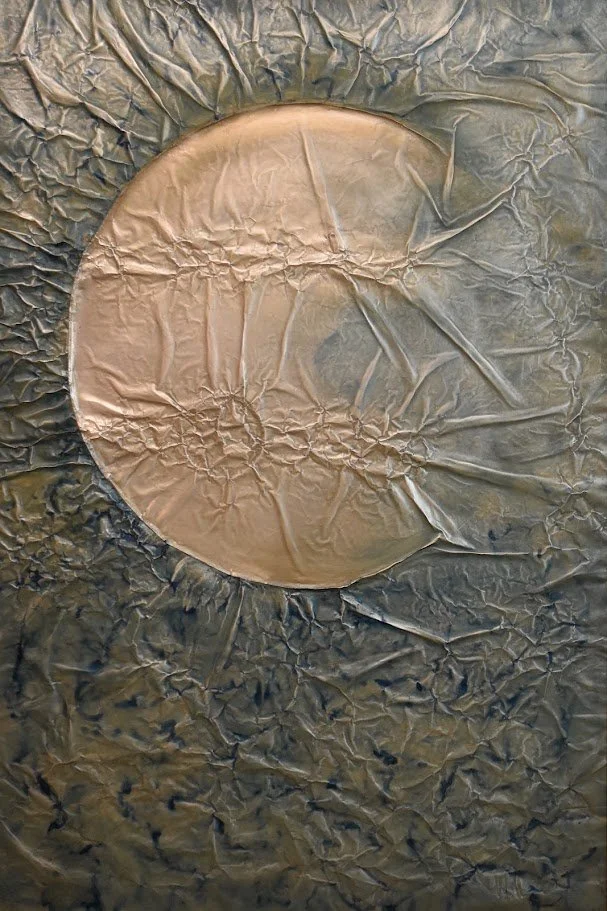 A copper orb emerges from a dark, textured metallic field. Shown close up without a frame.