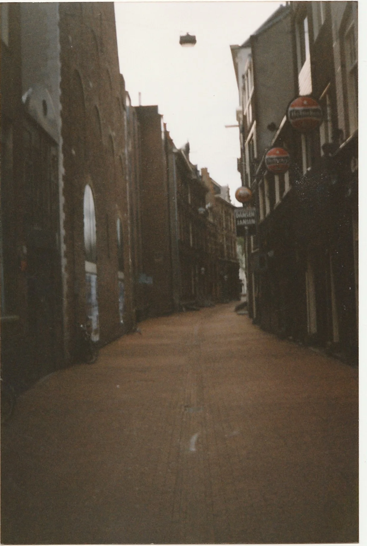 Narrow brick alleyway disappearing into shadow between historic buildings.