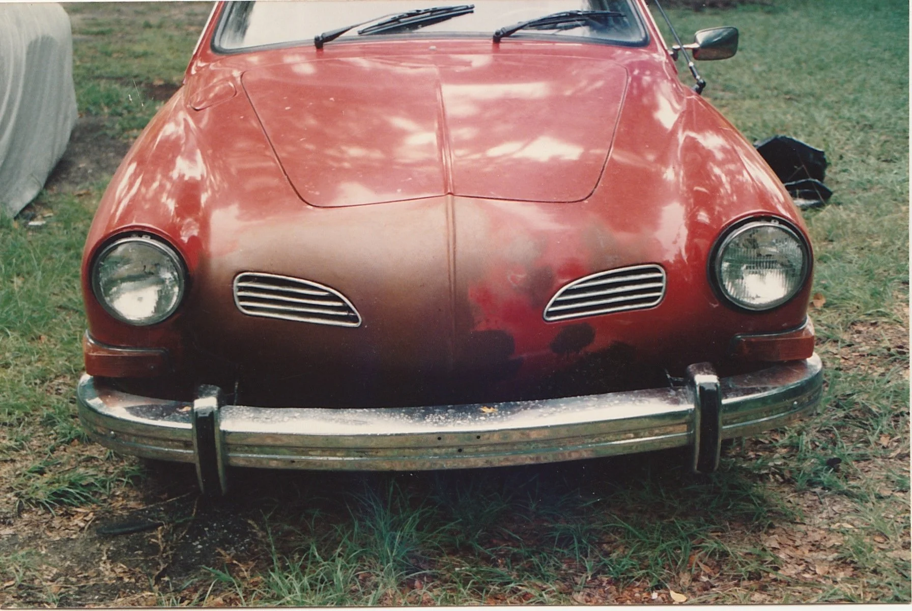 Front view of a vintage red automobile parked on grass.