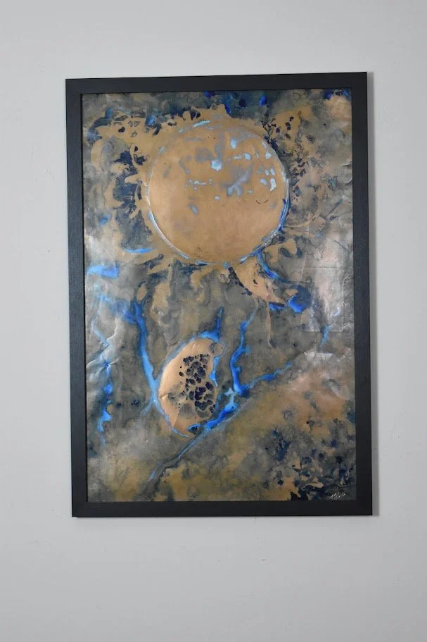 Golden planetary forms drift through smoky gray and vivid blue currents.