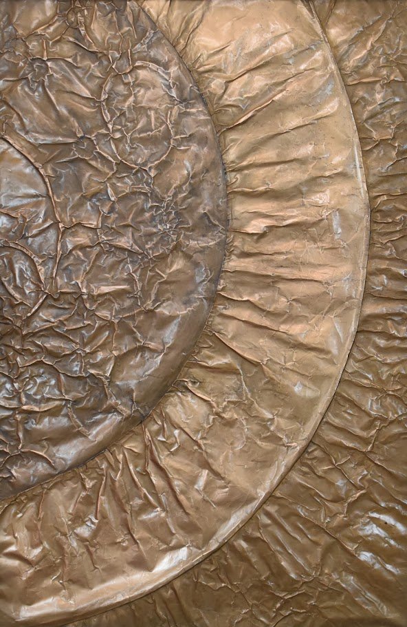 Concentric golden arcs radiate across a textured metallic field. Shown close up without a frame.