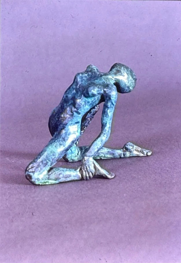 Small bronze figure kneeling on one knee, head lowered and fingertips touching the ground in a pose of exhaustion or contemplation.