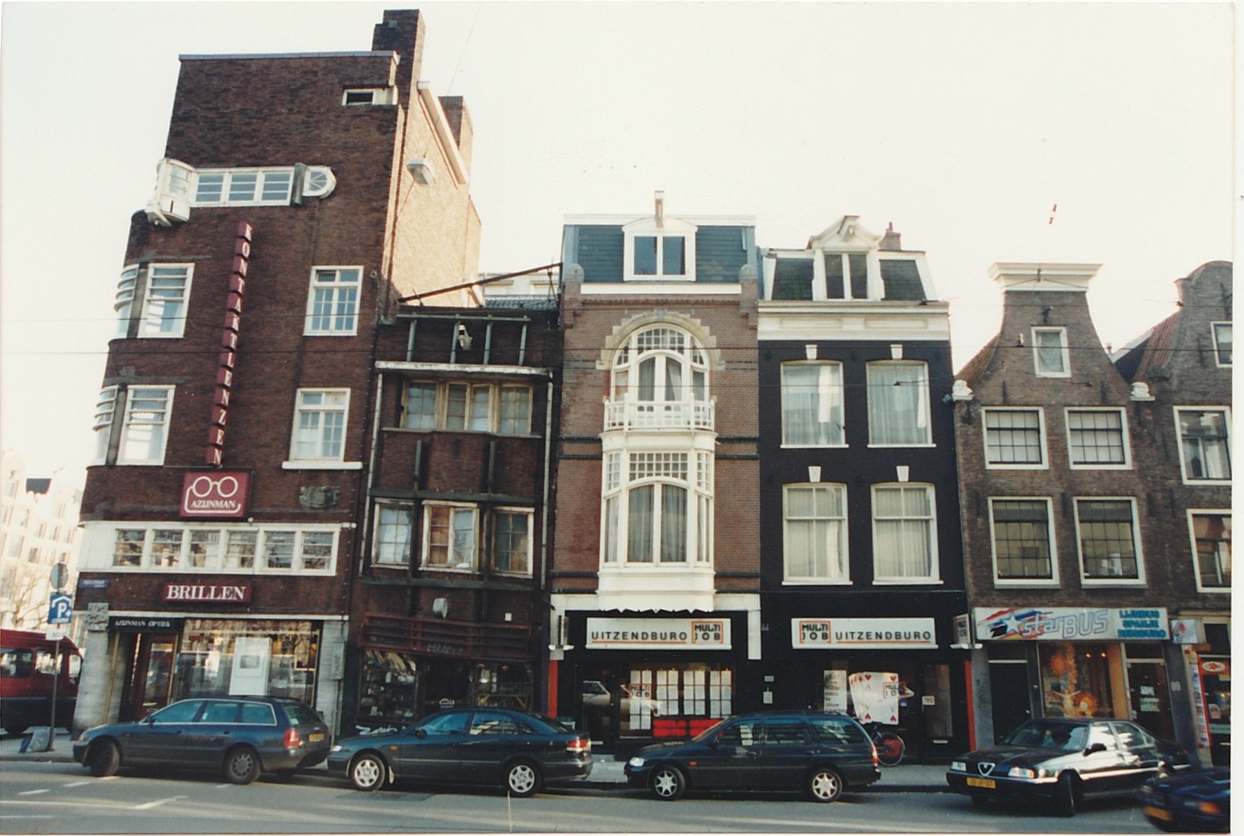 Row of narrow historic buildings lining a busy city street.