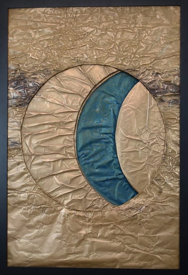 Interlocking golden and blue forms create a planetary eclipse. Shown close up in a black frame.