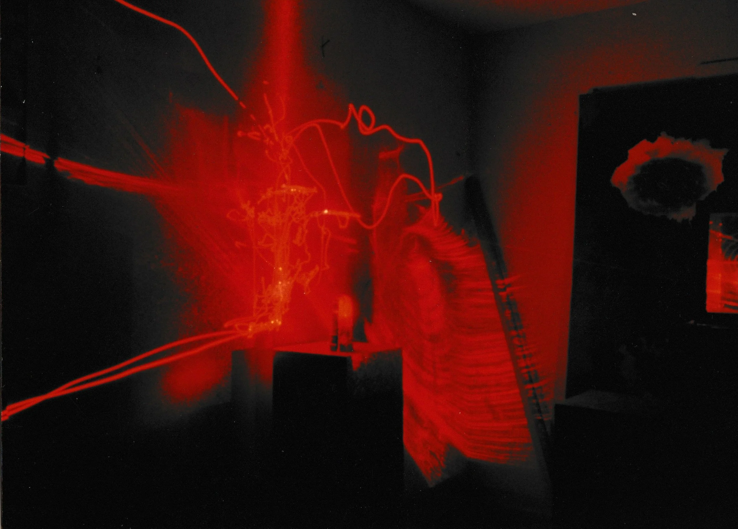Abstract circular form glowing with red-orange light against a dark background, surrounded by textured laser patterns.