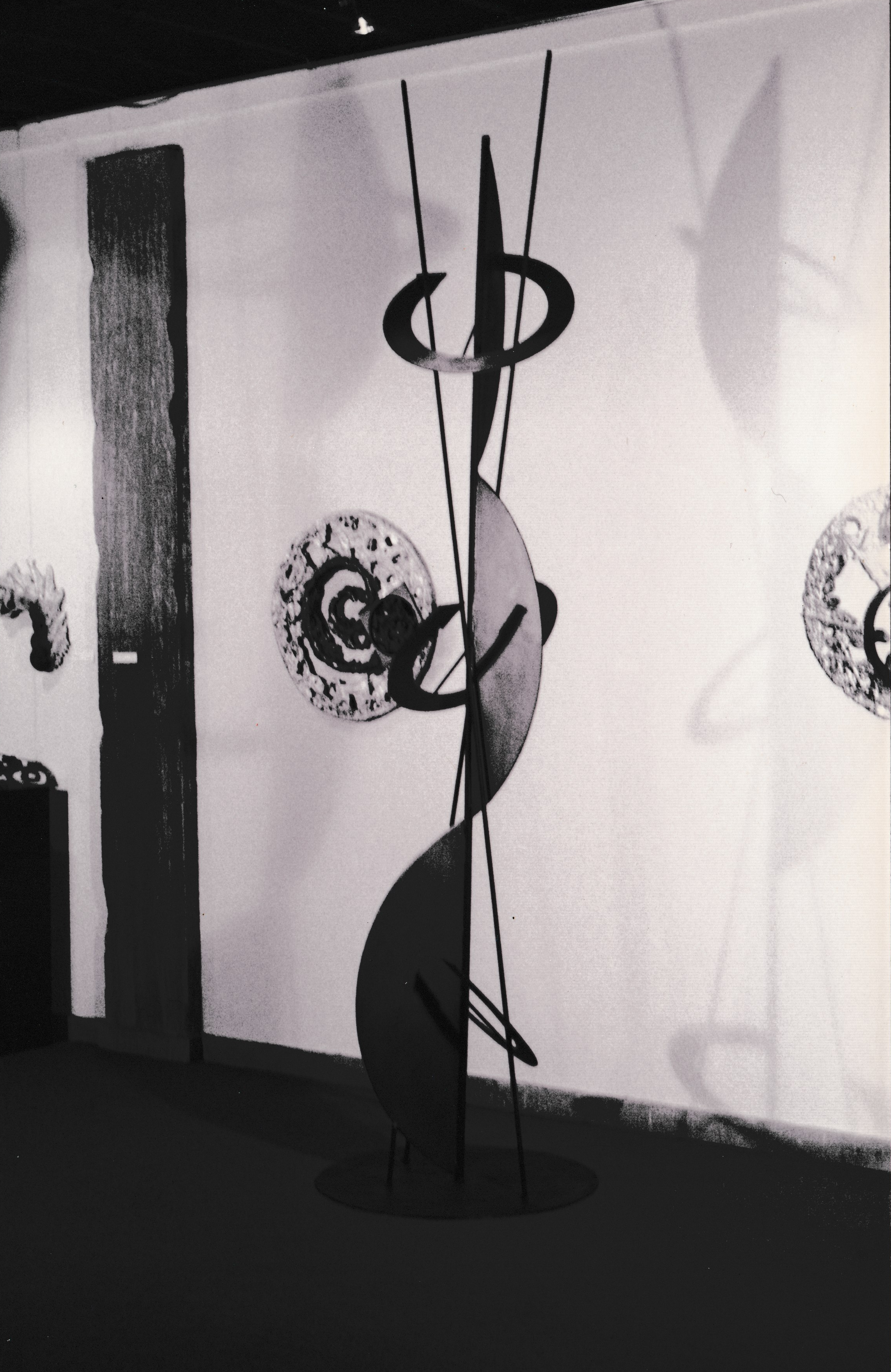 Tall black-and-white sculpture featuring suspended rings and sweeping curved forms mounted on a circular base.
