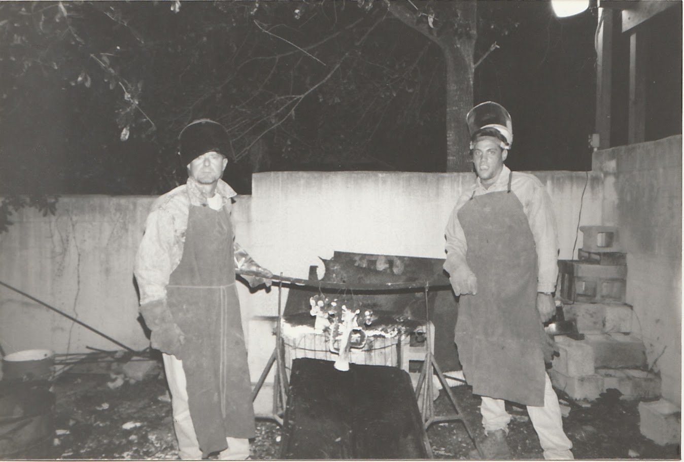 Whitney Wolf II teaching students to cast bronze. Black-and-white photo. EST 1980s