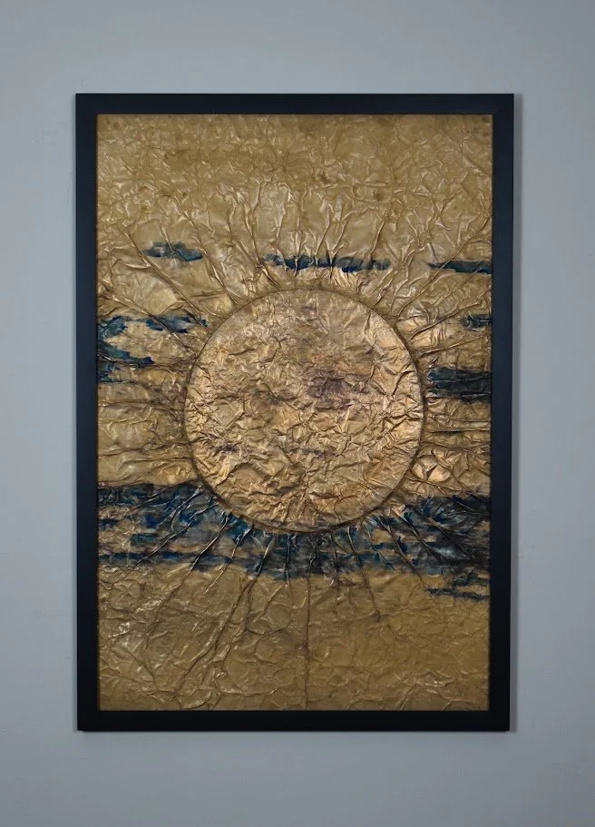 A golden orb radiates through dark horizontal currents. Displayed framed on a white wall.