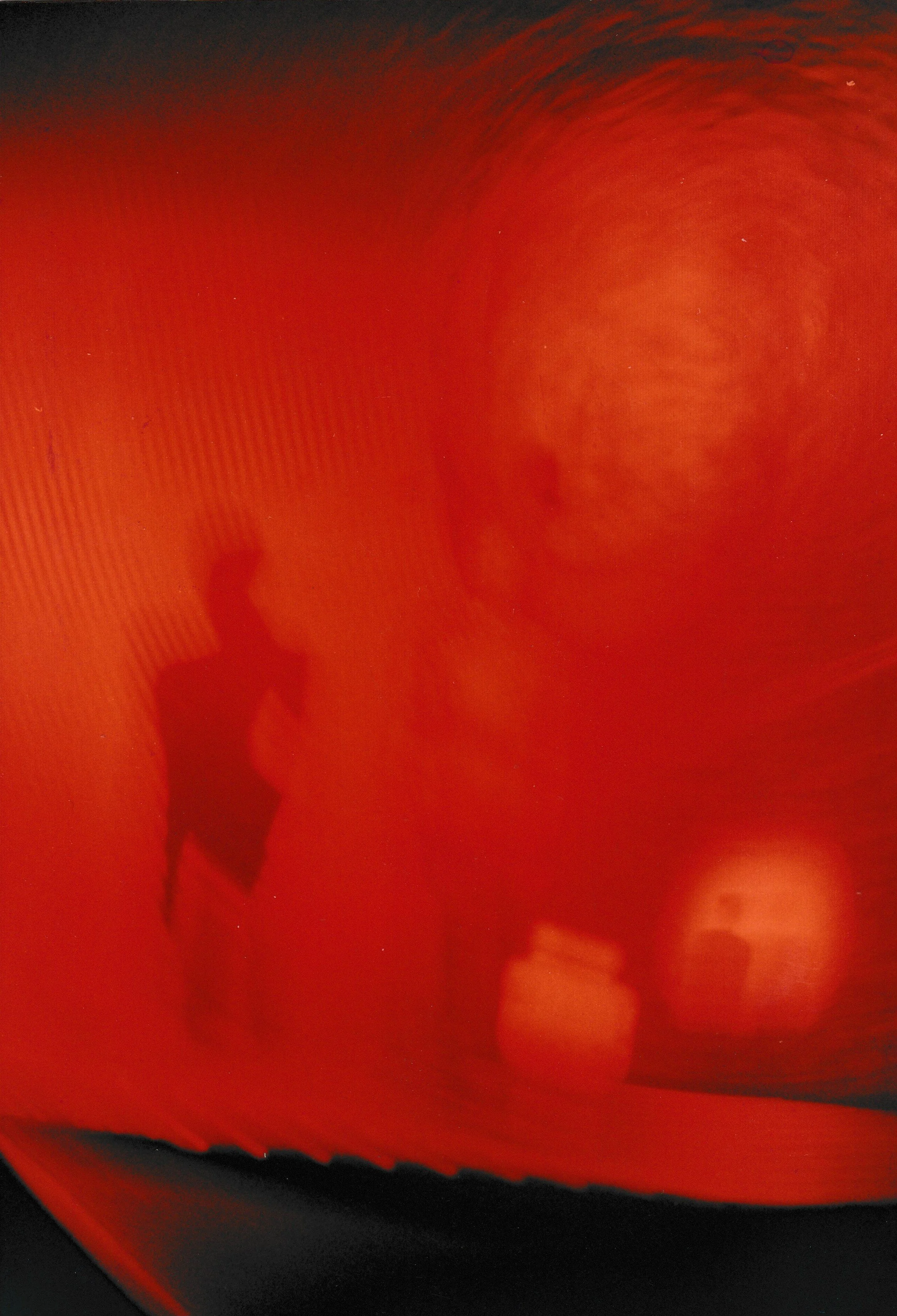 Dark exhibition space featuring red laser projections crossing between sculptural elements and reflective surfaces.