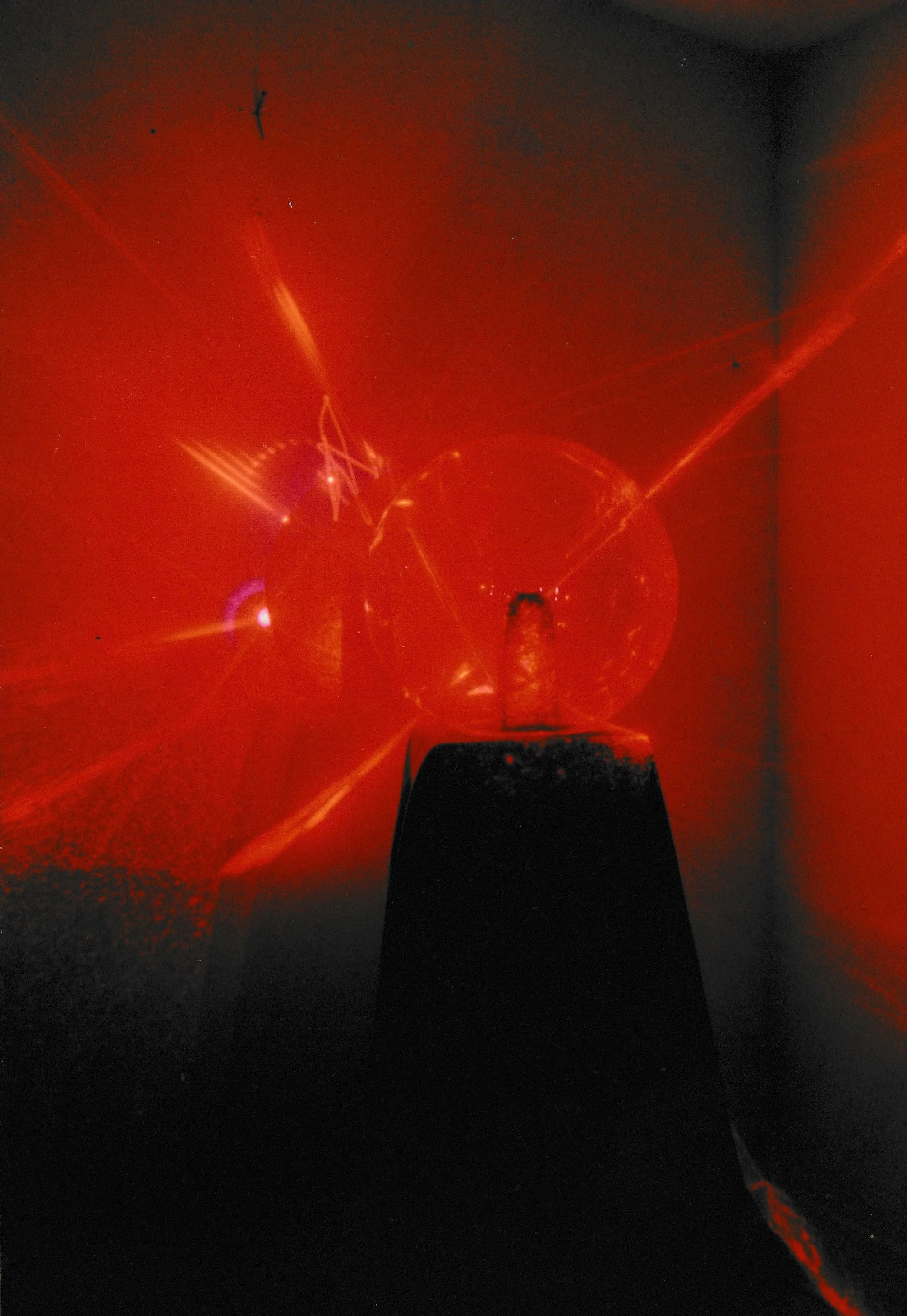 Grid-like structure illuminated by a central red light source, creating intersecting geometric patterns across the scene.