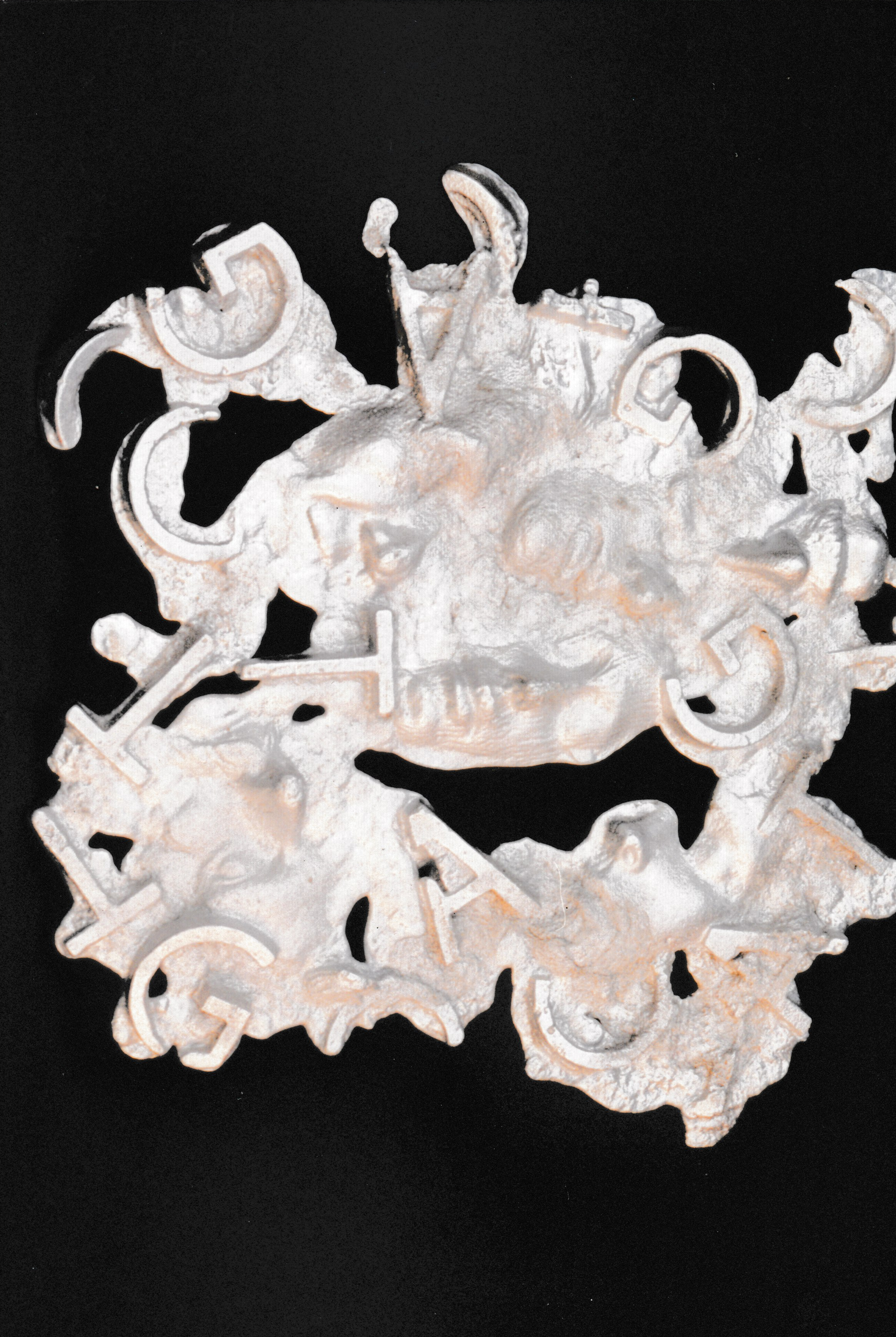 White sculpture featuring overlapping faces and abstract forms arranged in a dense composition.