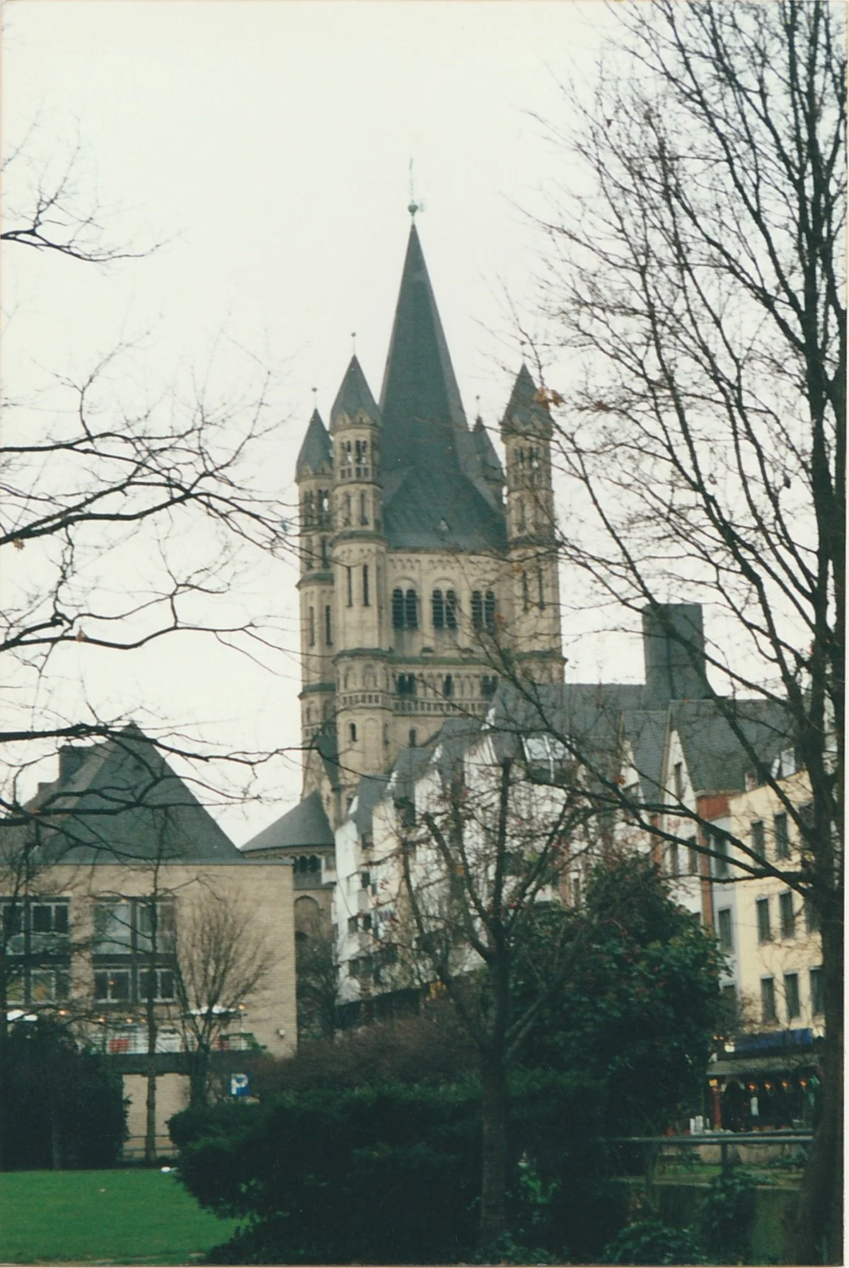 Historic church tower rising above a landscaped garden and neighboring buildings.