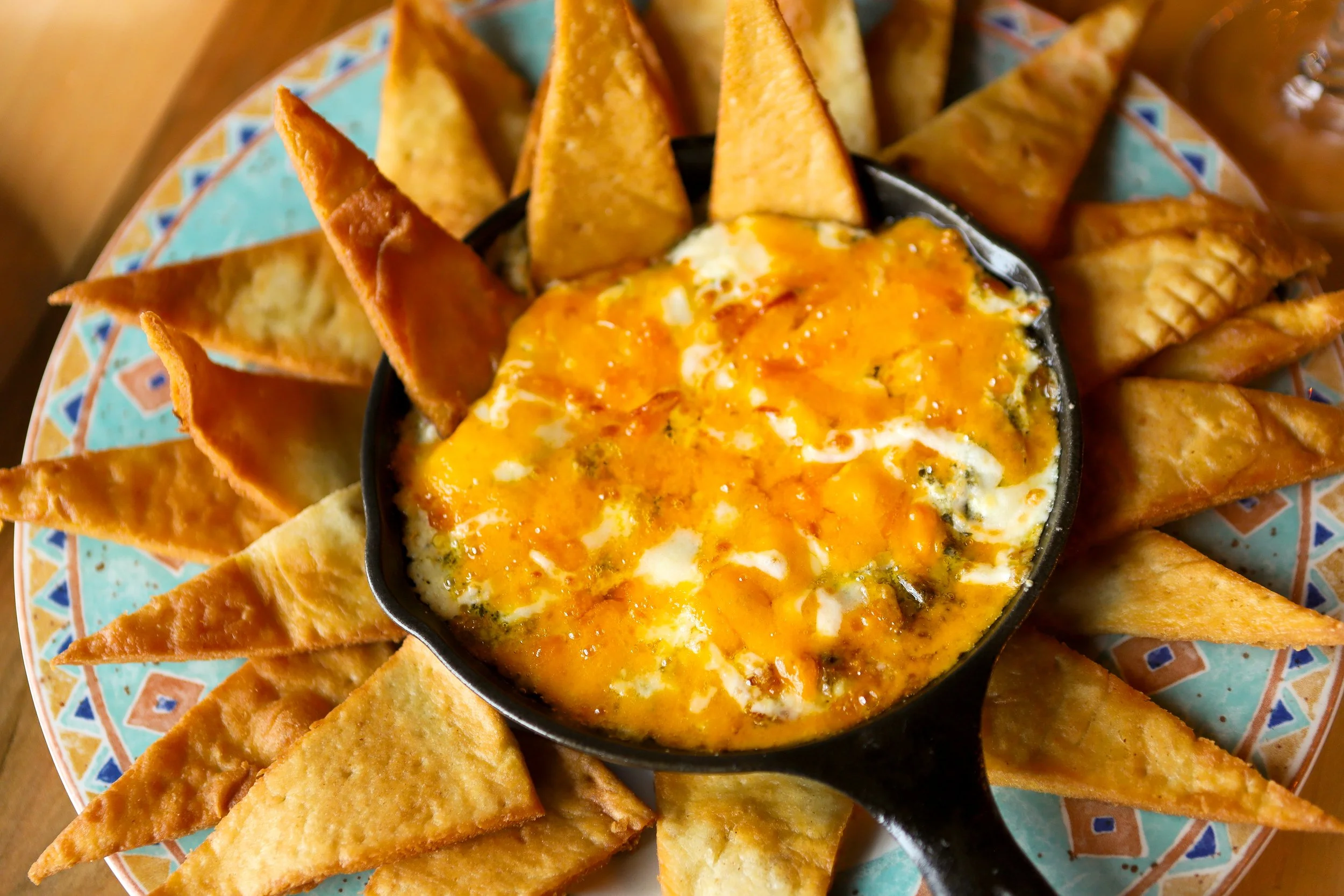 The Bruce's famous spinach dip. A plate of fried tortilla chips with a small bowl of cheesy spinach dip in the centre.