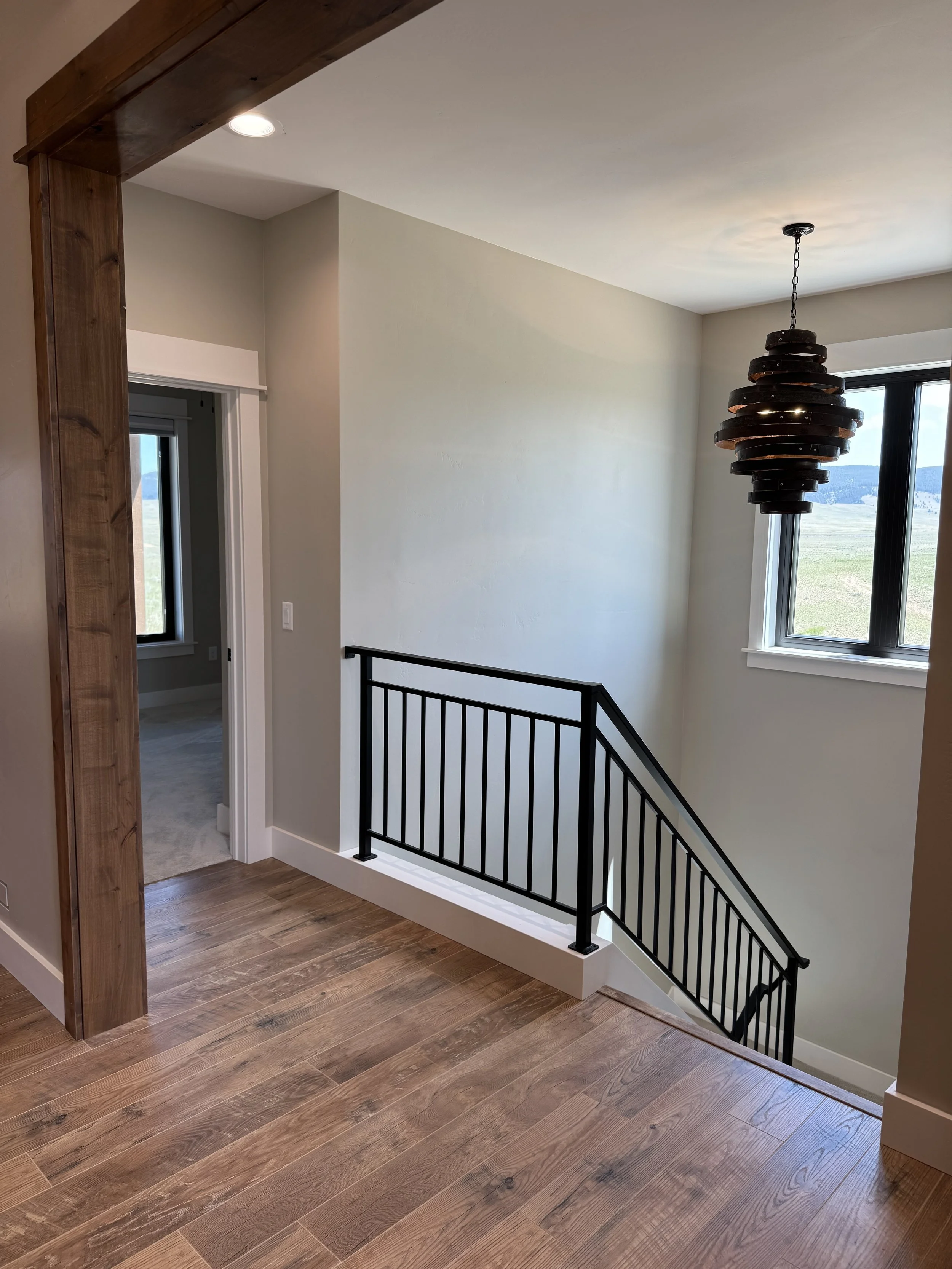 Custom loft staircase with designer metal railing — luxury timber frame home by Mihelich Custom Builders near Butte, Montana.