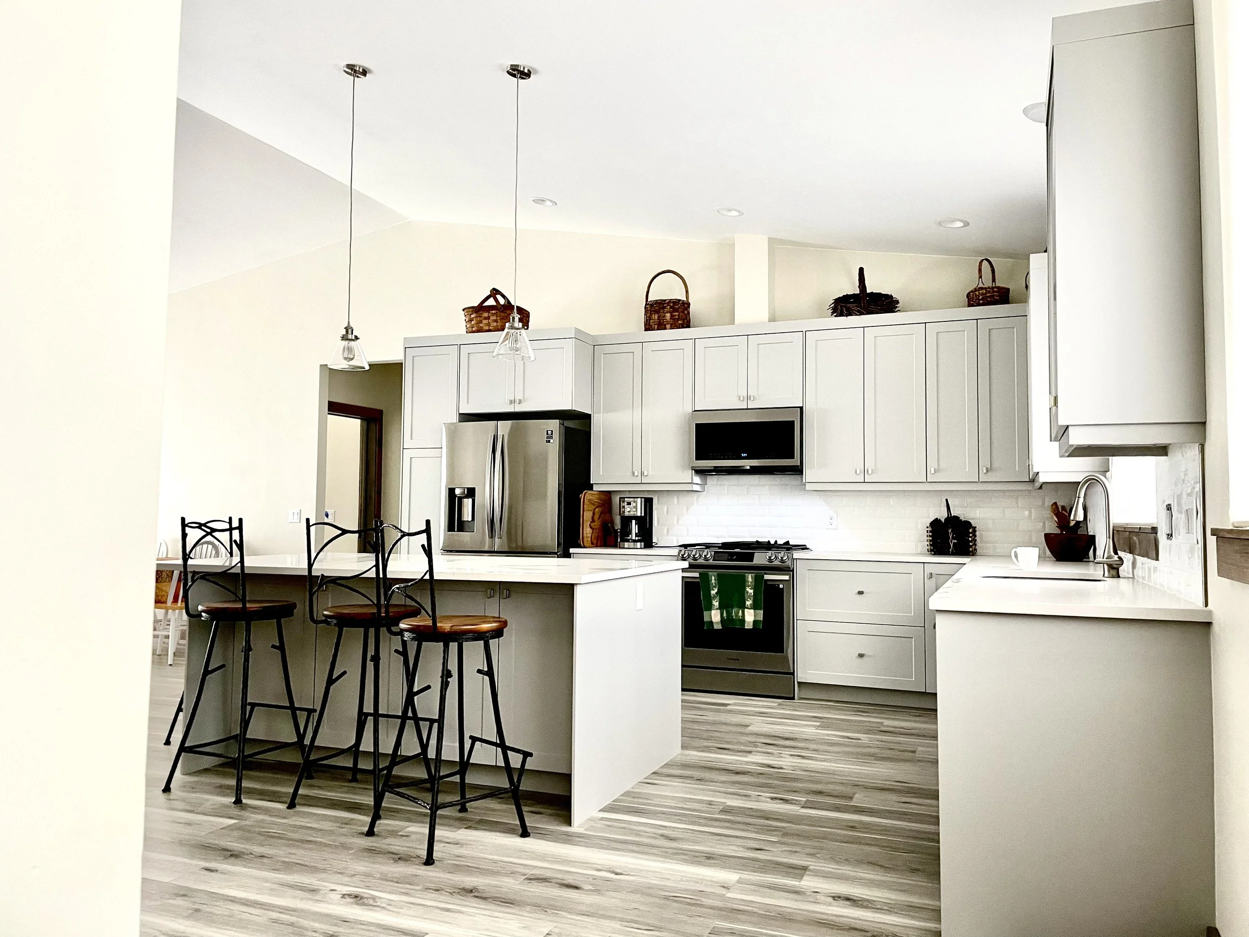 Custom kitchen with bar seating, designer pendants, and mountain-modern finishes — Montana custom home builder Mihelich Custom Builders.