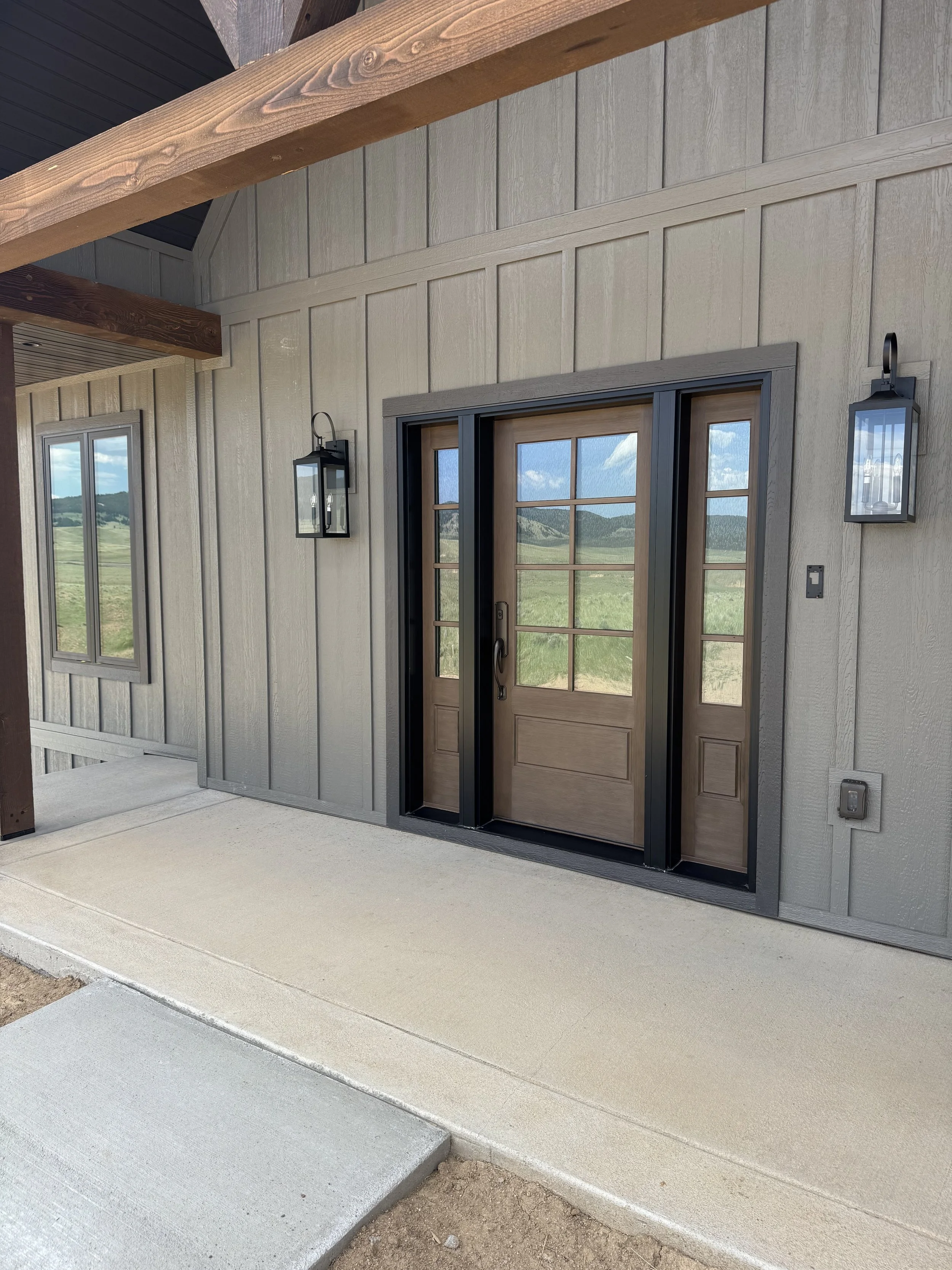 Custom covered entry with designer wall sconce and French doors — mountain home craftsmanship by Mihelich Custom Builders near Butte, Montana.