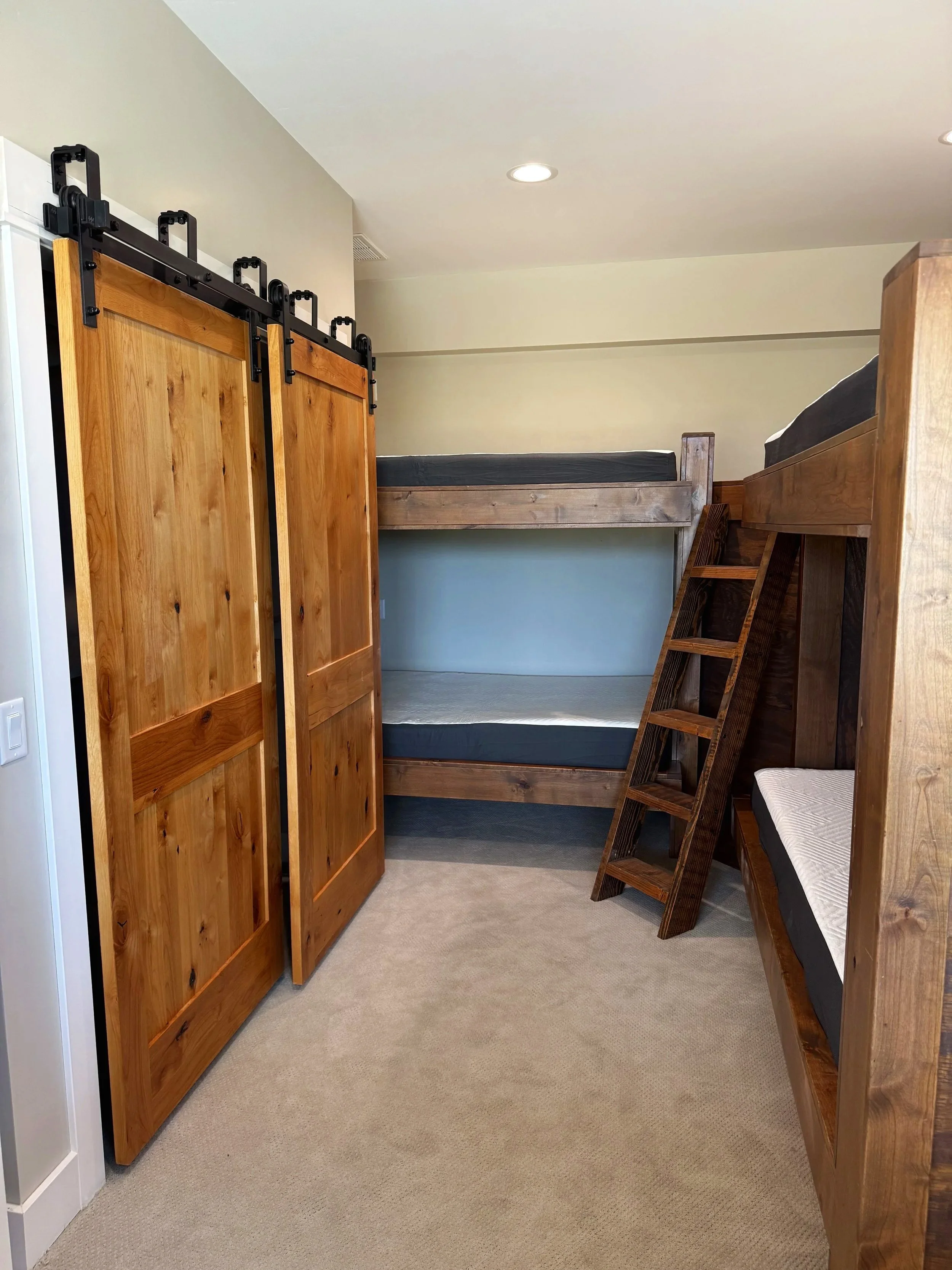 Custom barn door entry to bunk room with built-in beds — luxury Montana mountain home construction by Mihelich Custom Builders near Butte.