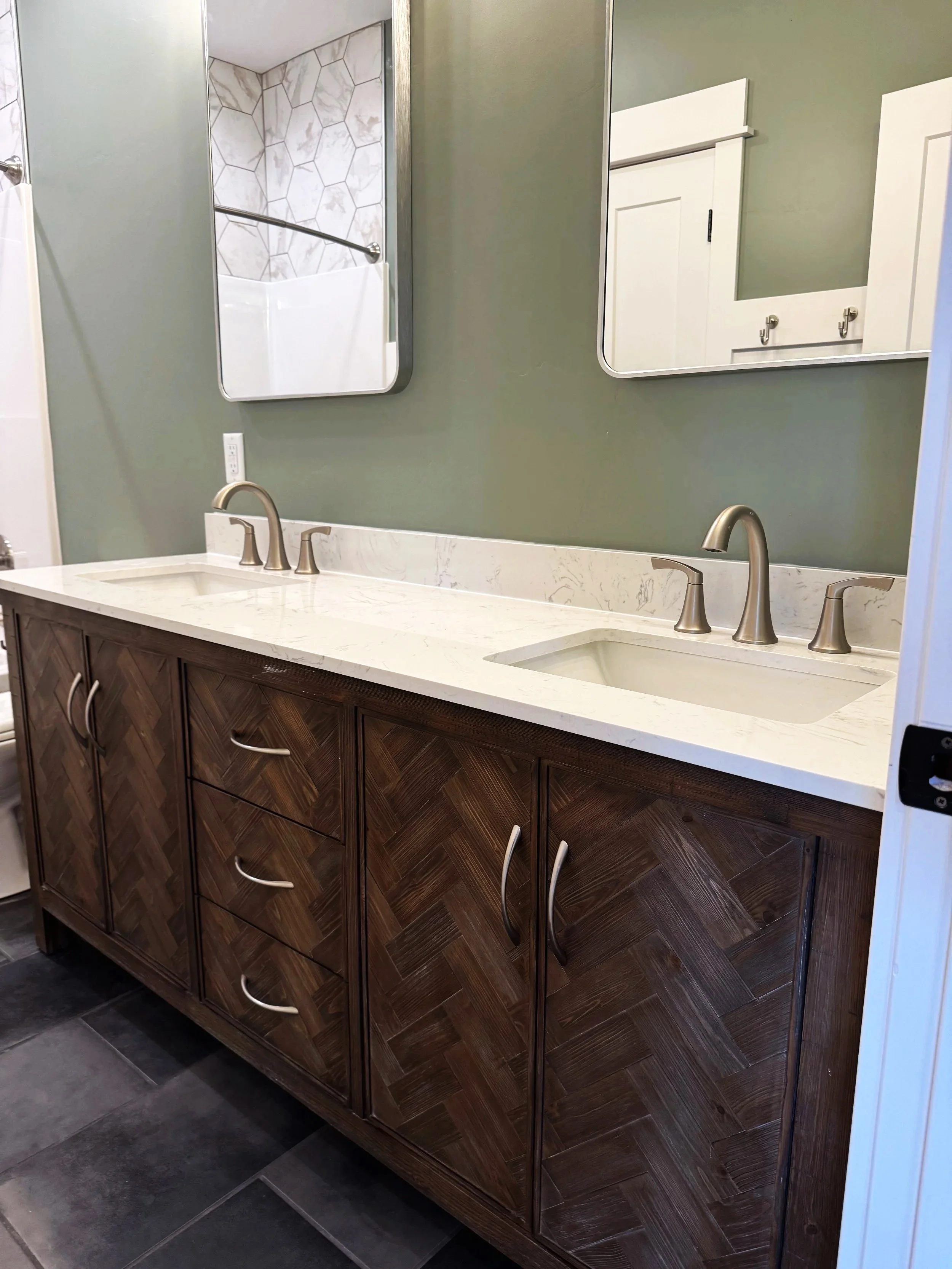 Custom bathroom with double vanity and dark cabinetry — high-end bathroom finishes by Mihelich Custom Builders near Butte, Montana.