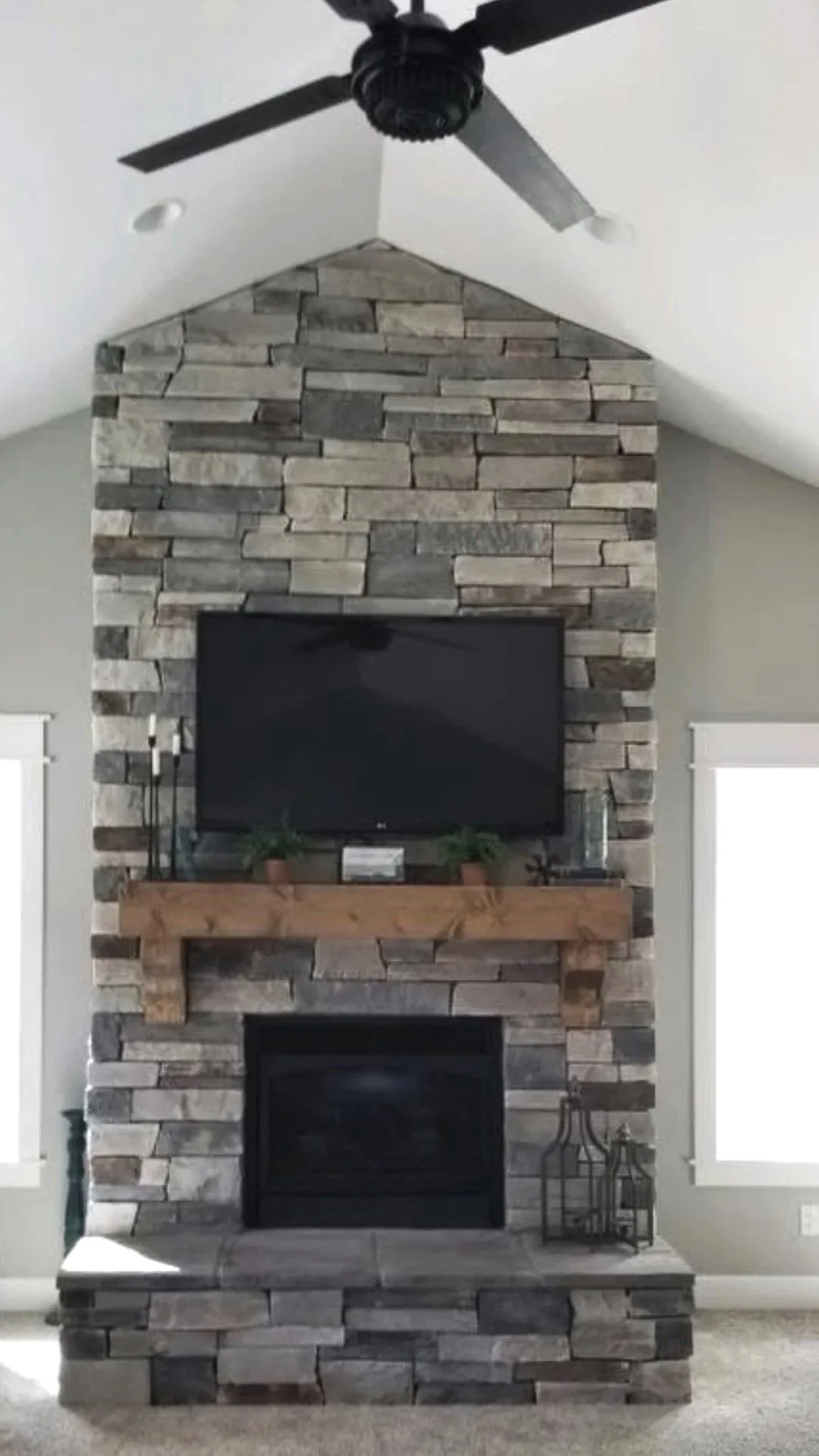 Custom stacked stone fireplace with wood mantel and mounted TV — luxury custom home in Butte, Montana by Mihelich Custom Builders.