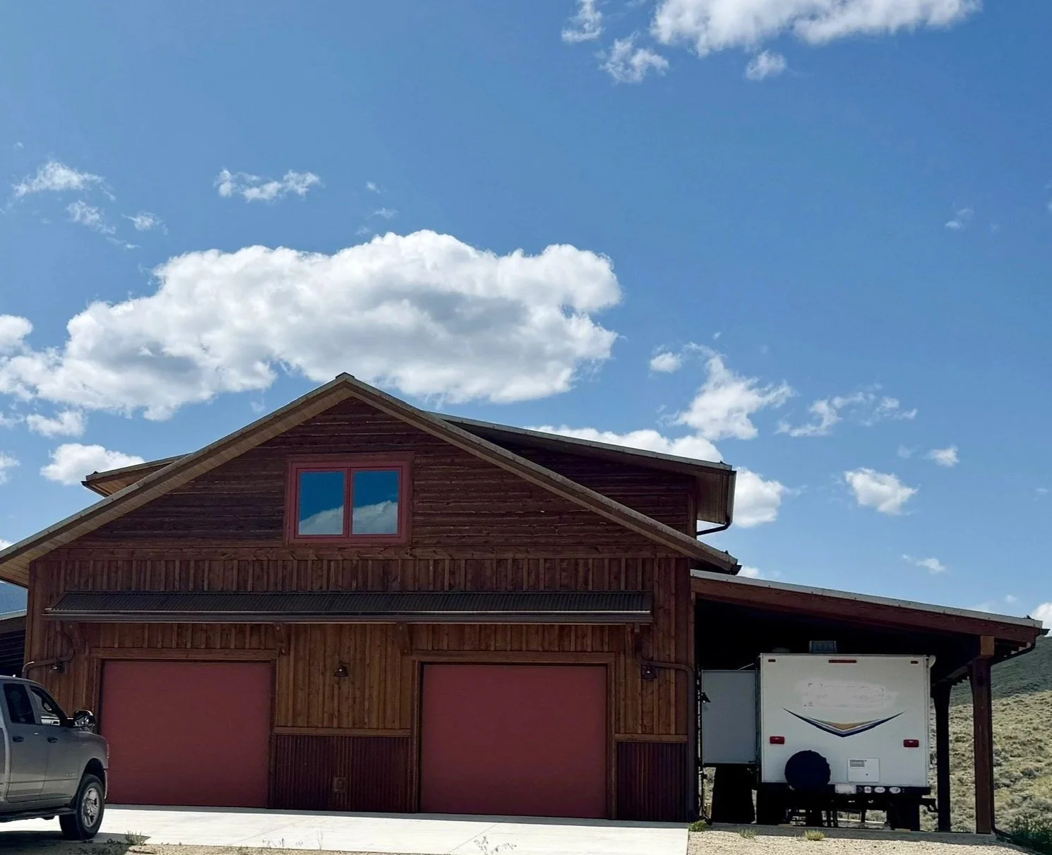 Custom wood exterior with covered entry and Montana landscape — Mihelich Custom Builders, Glen, MT.