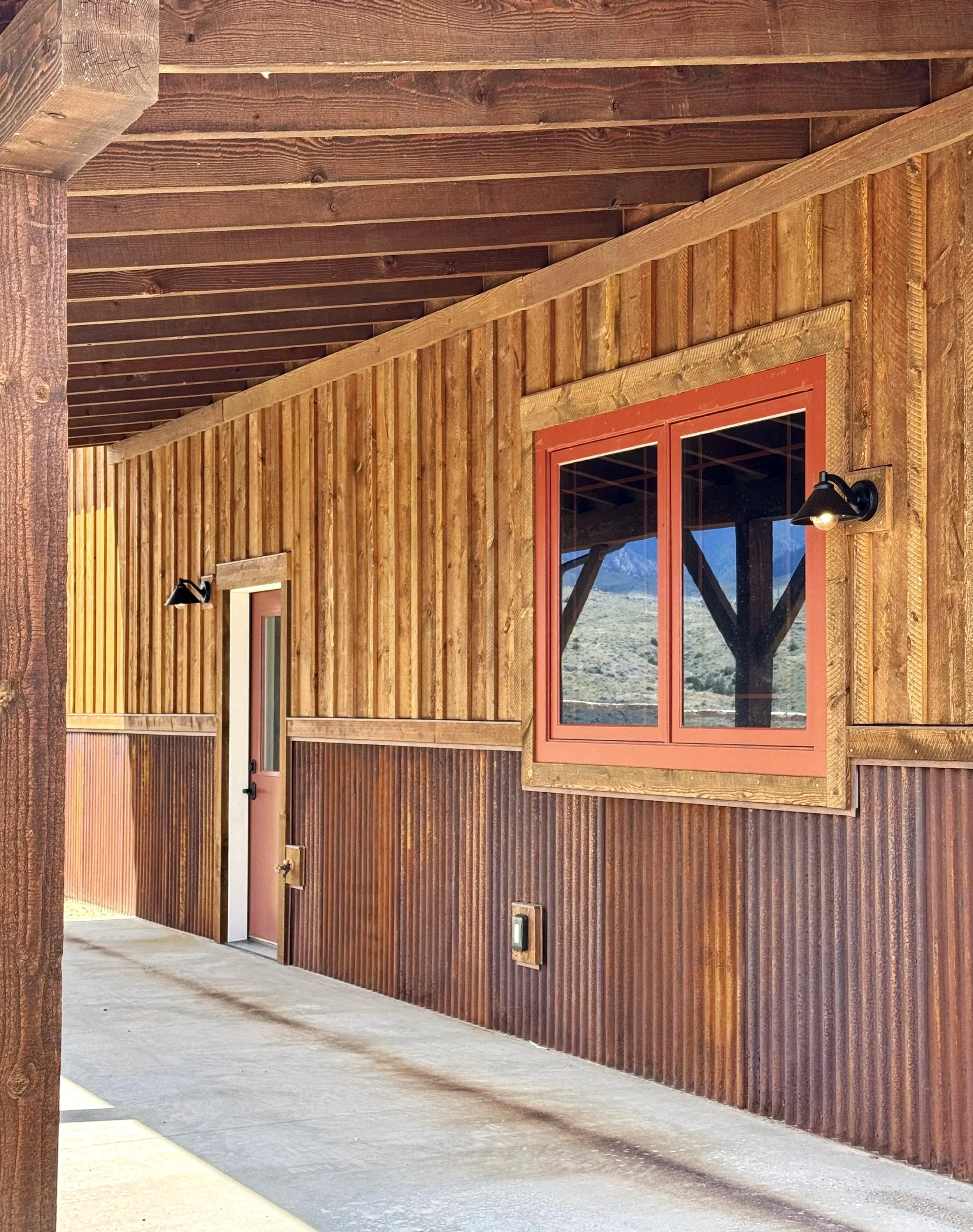 Custom home with wraparound covered porch and wood exterior — luxury rustic construction by Mihelich Custom Builders, Glen, MT.