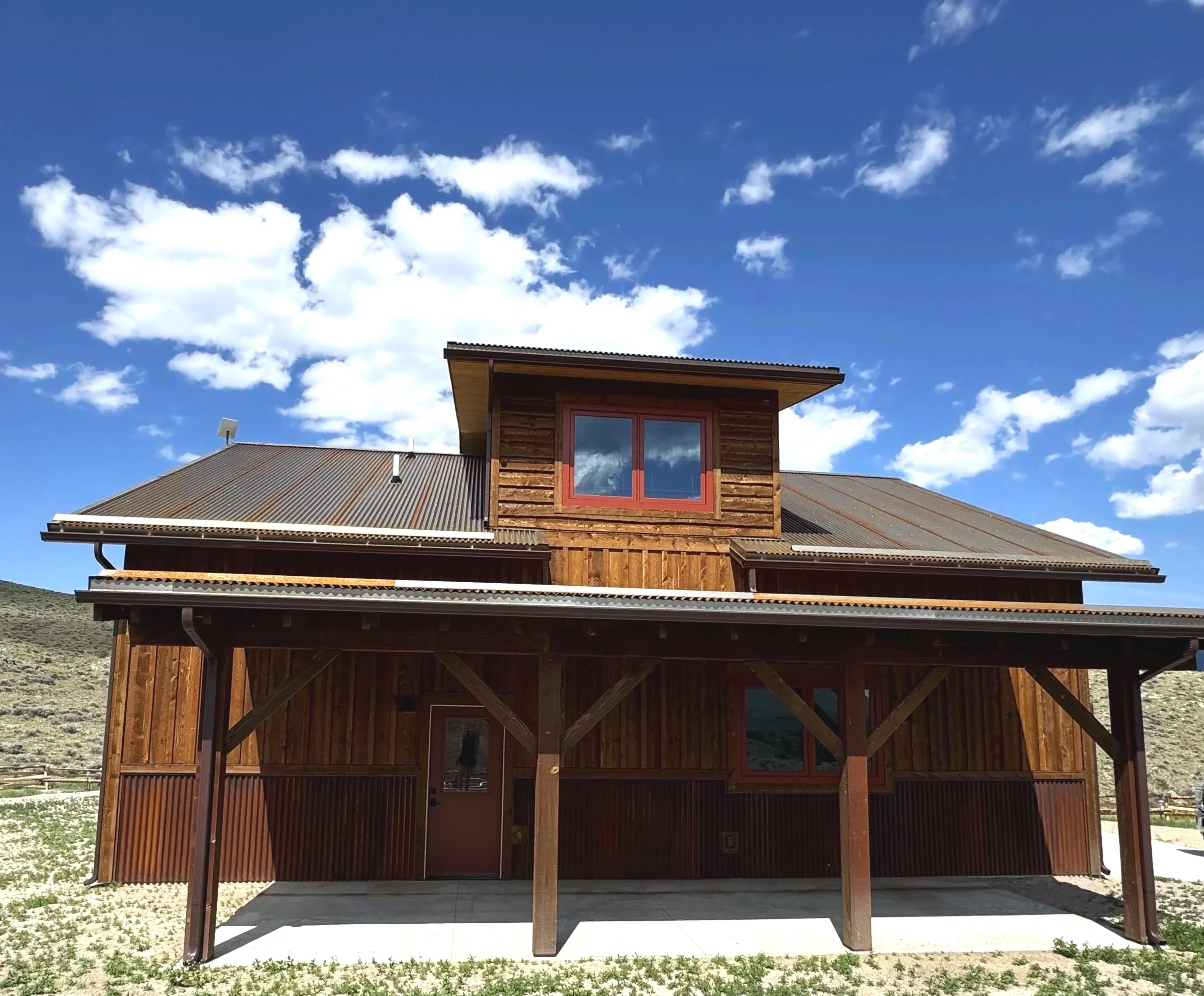 Custom home with wraparound covered porch and wood exterior — luxury rustic construction by Mihelich Custom Builders, Glen, MT.