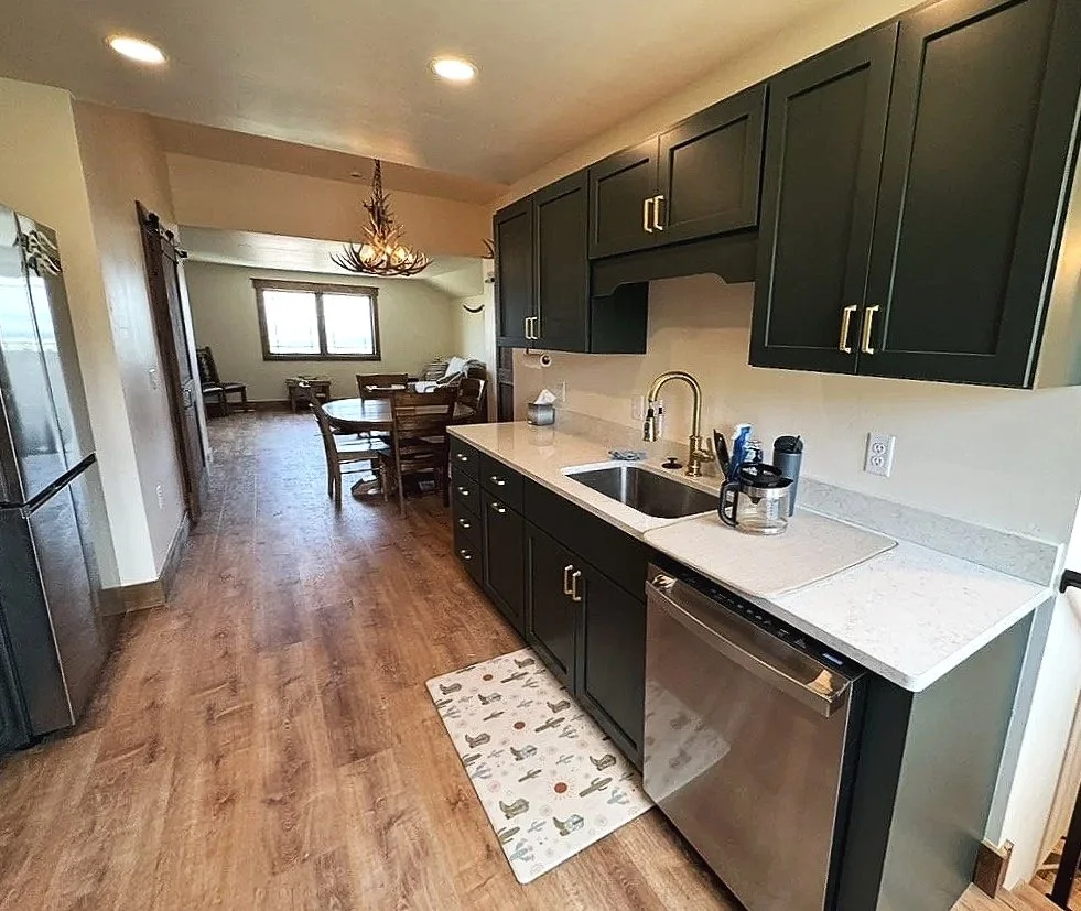 Custom open-concept living and kitchen area with hardwood floors — luxury rustic home by Mihelich Custom Builders, Glen, MT.