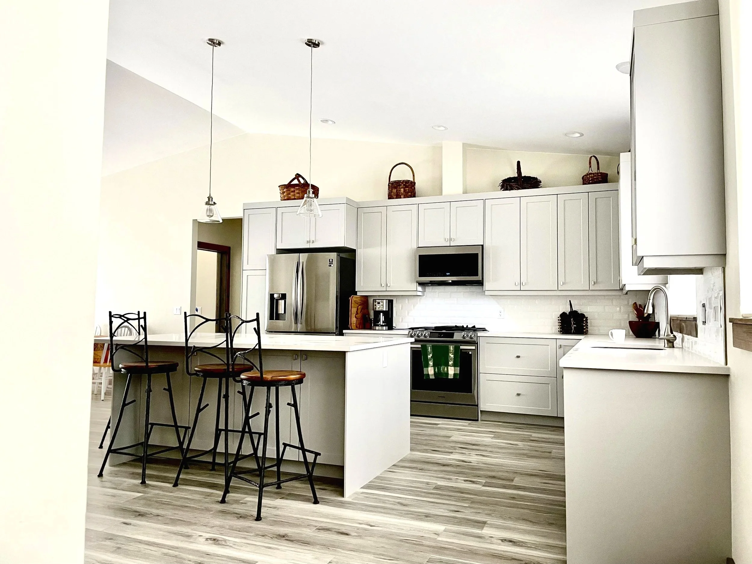 Custom kitchen with white cabinets, black stools, and wood floors