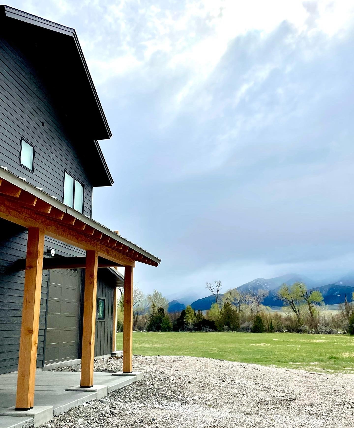 Custom barndominium with covered entry, mixed materials, and Montana mountain views — Mihelich Custom Builders, Silver Star, MT.