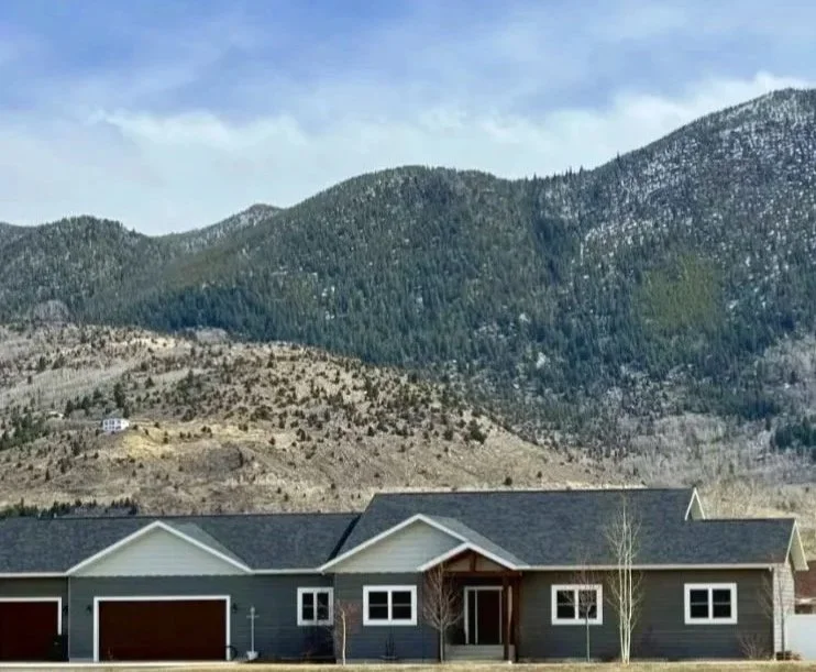 Custom modern home with dark exterior and mountain backdrop — luxury custom home builder Mihelich Custom Builders, Butte, Montana​​​​​​​​​​​​​​​​
