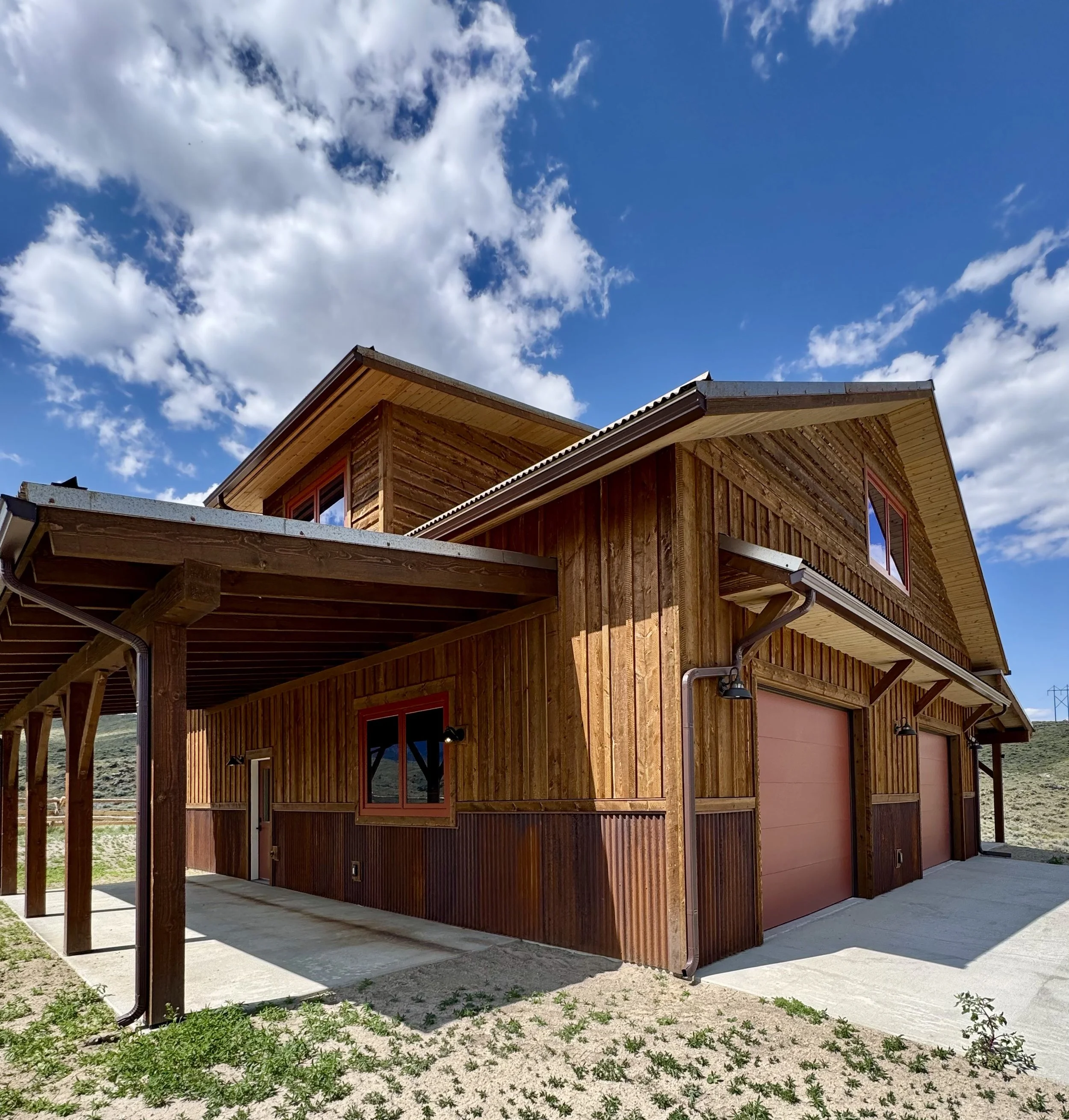 Custom rustic residence exterior with natural wood siding under Montana big sky — Mihelich Custom Builders, Glen, Montana.