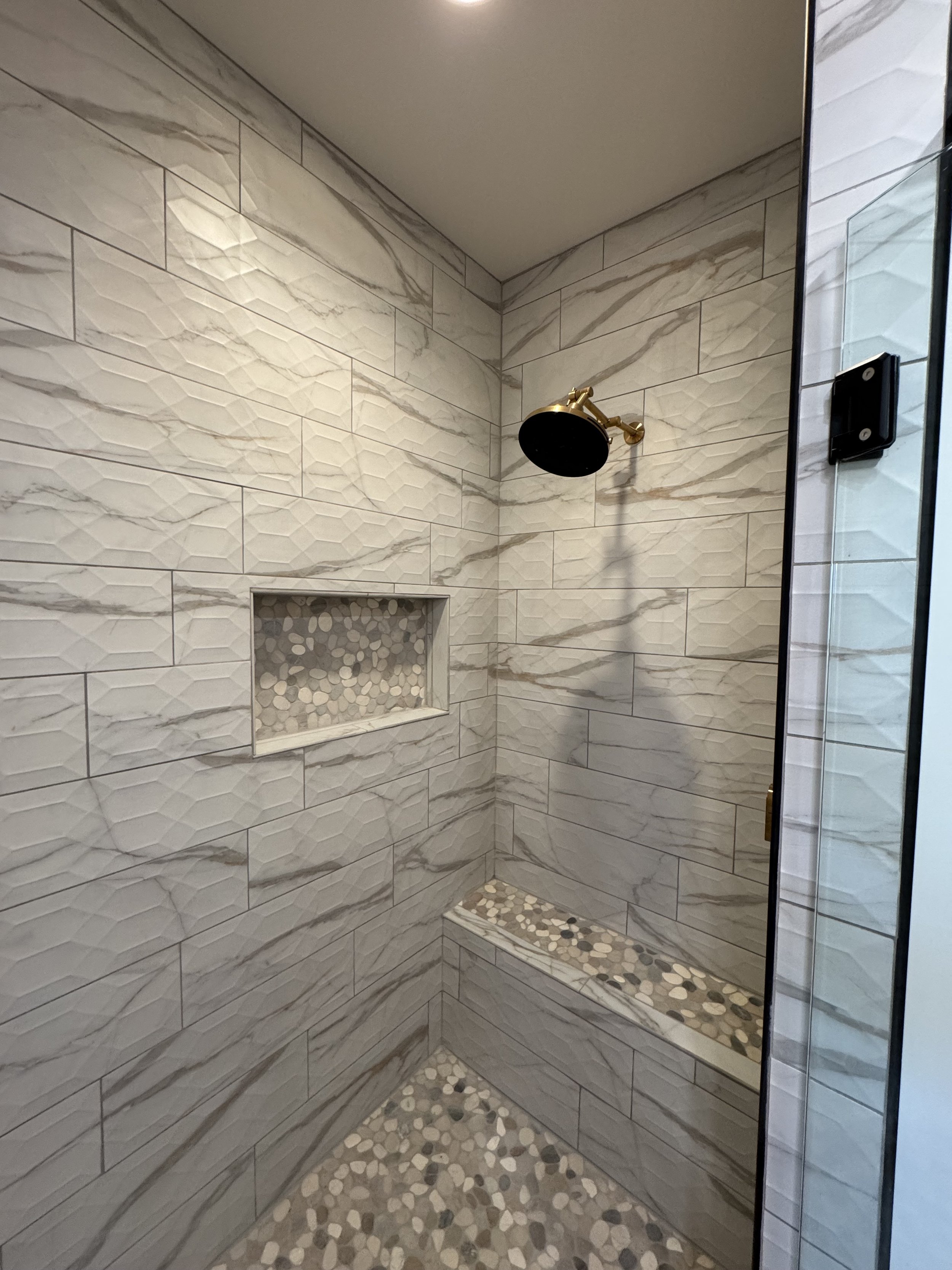 Custom stone shower with designer wall sconce — spa-inspired bathroom by Mihelich Custom Builders near Butte, Montana