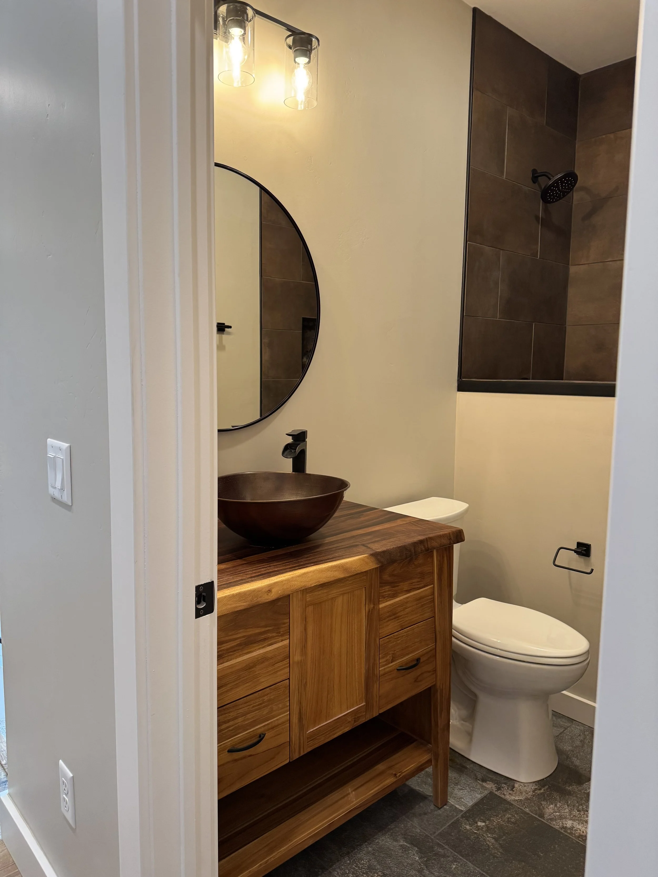 Custom primary bathroom with vessel sink, wood vanity, and statement mirror — luxury Montana home by Mihelich Custom Builders near Butte, MT.