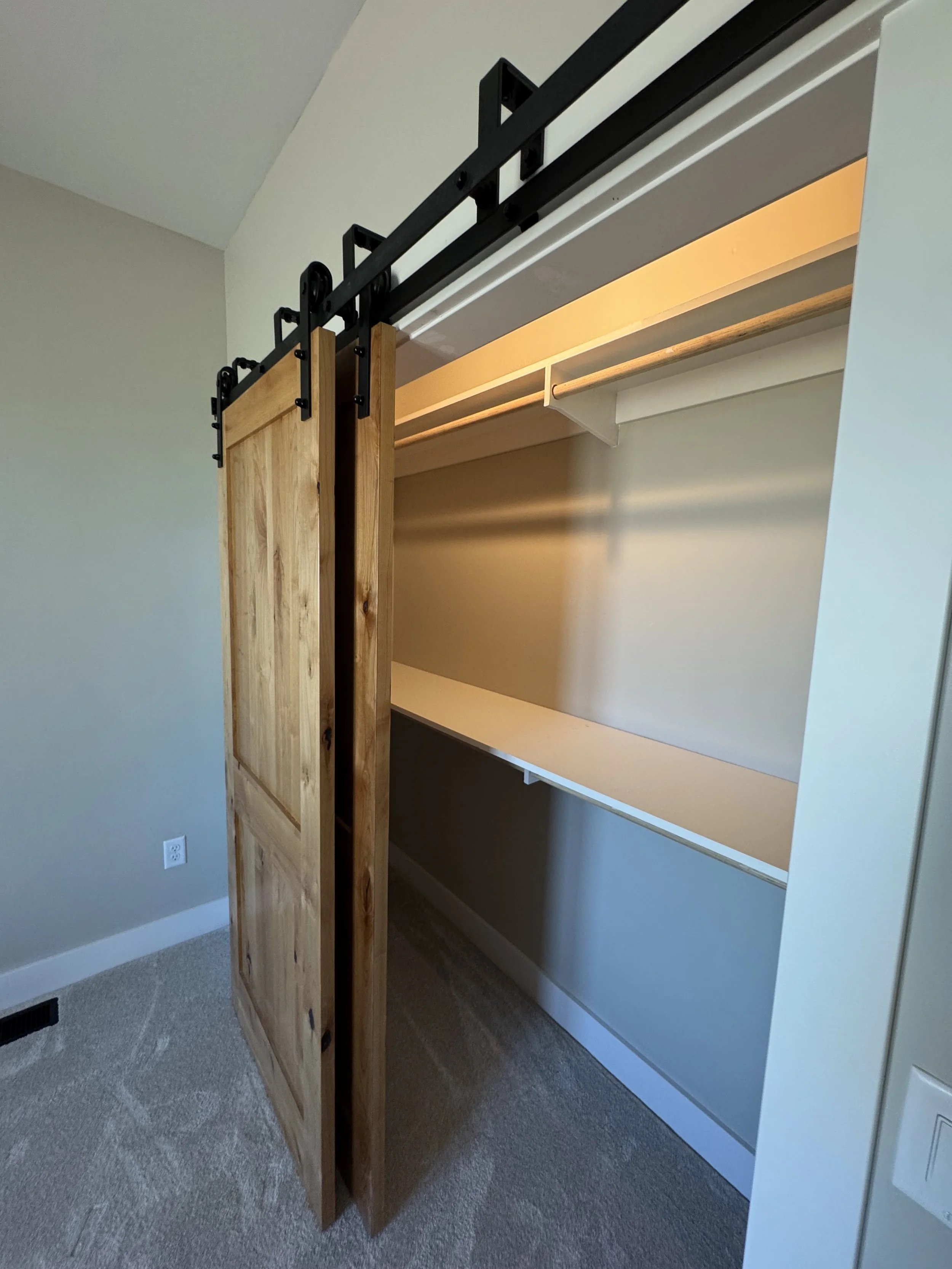 Custom barn door closet with built-in shelving — luxury bedroom storage by Mihelich Custom Builders near Butte, Montana