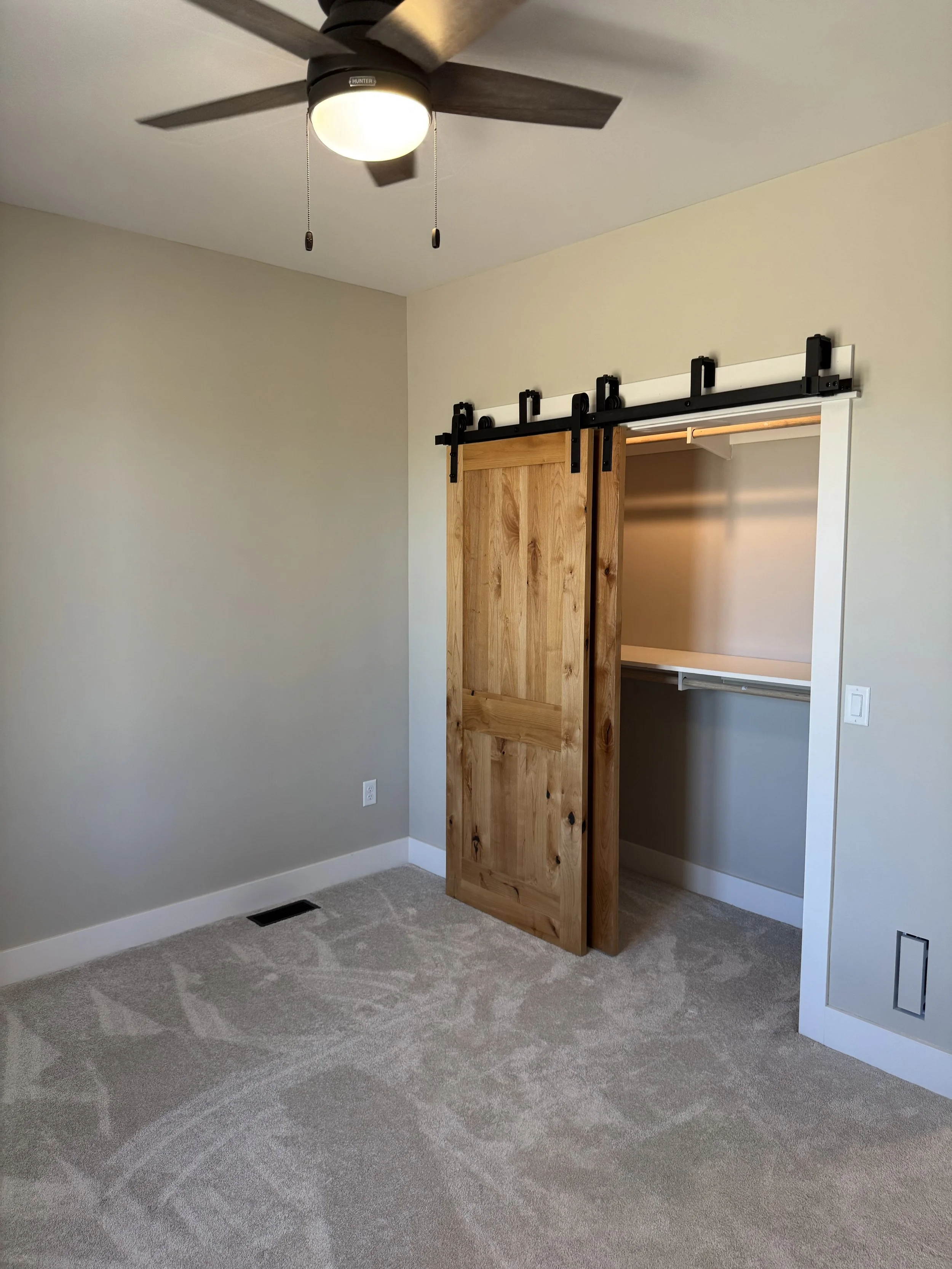 Custom barn door closet with built-in shelving — luxury bedroom storage by Mihelich Custom Builders near Butte, Montana.