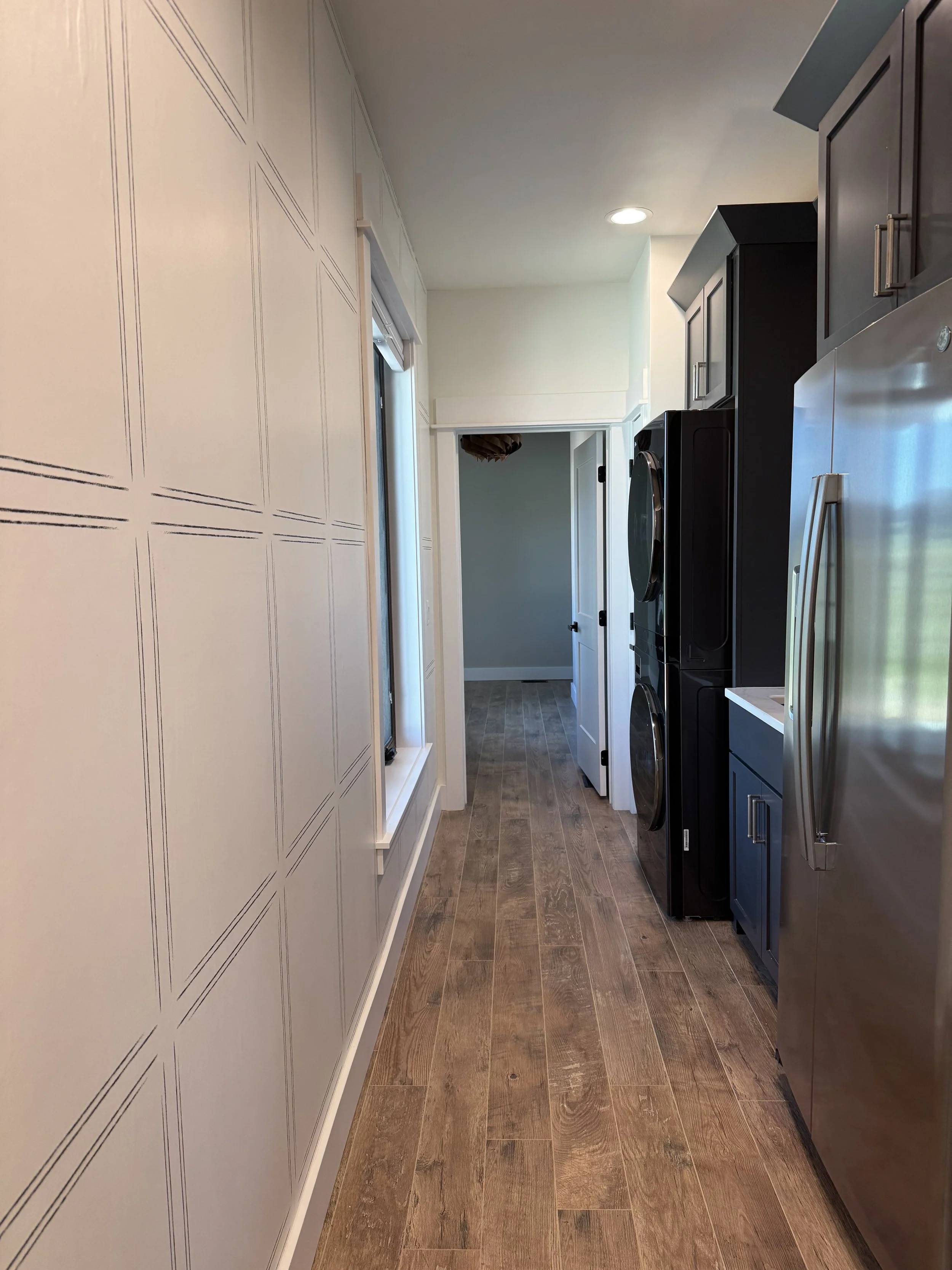 Custom laundry room with stacked washer/dryer and built-in cabinetry — functional luxury design by Mihelich Custom Builders near Butte, Montana.