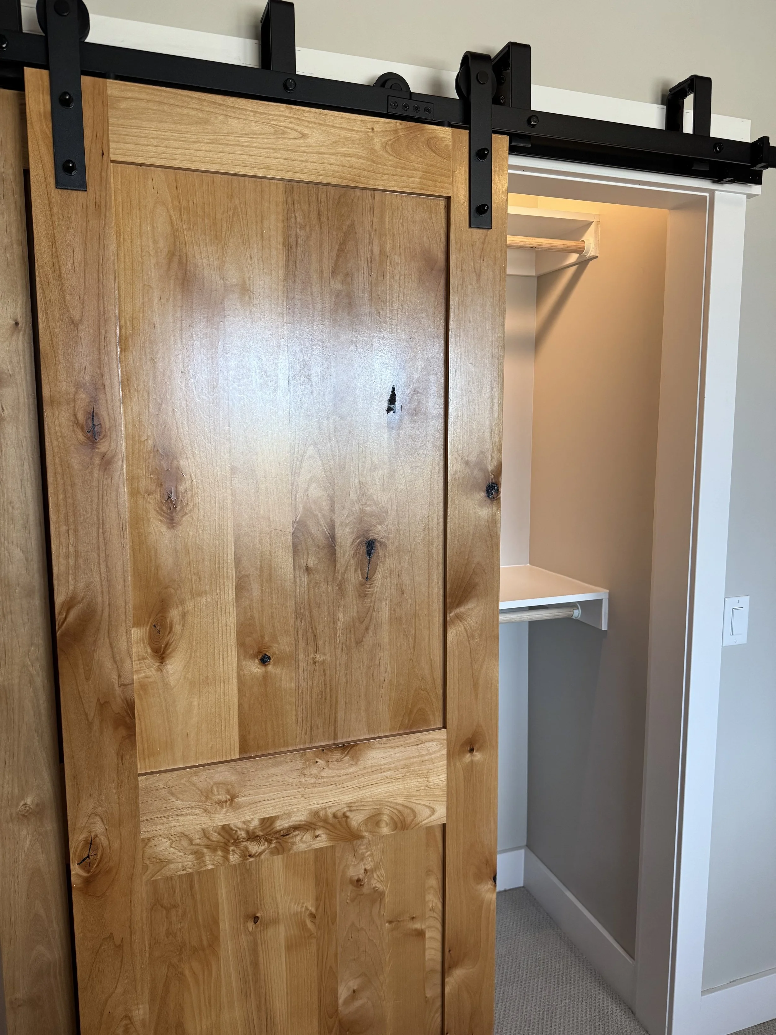 Custom knotty alder sliding barn door — signature interior detail by Mihelich Custom Builders, luxury home near Butte, Montana.