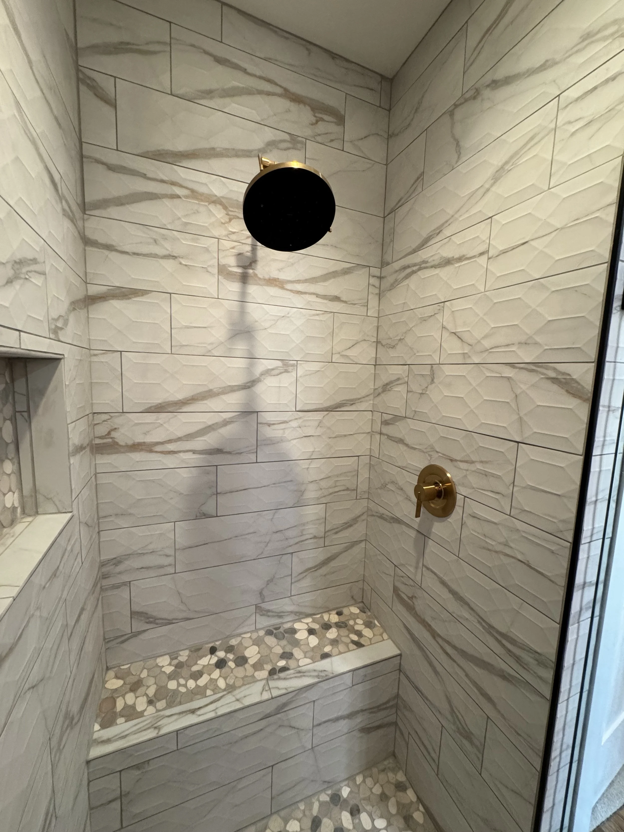 Custom stone feature wall in luxury shower — high-end bathroom construction by Mihelich Custom Builders near Butte, MT.
