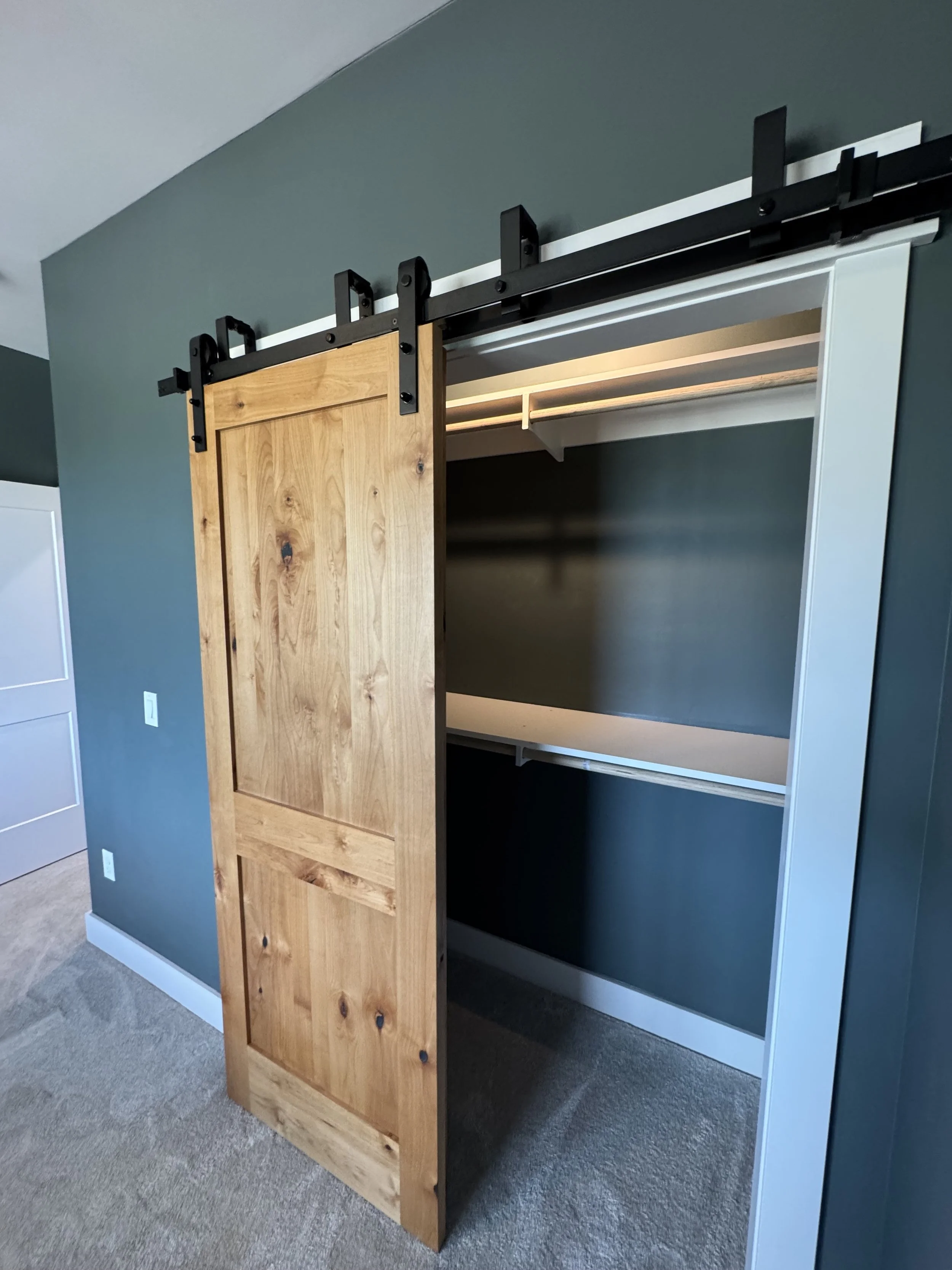 Custom barn door closet with built-in shelving — luxury bedroom storage by Mihelich Custom Builders near Butte, Montana.