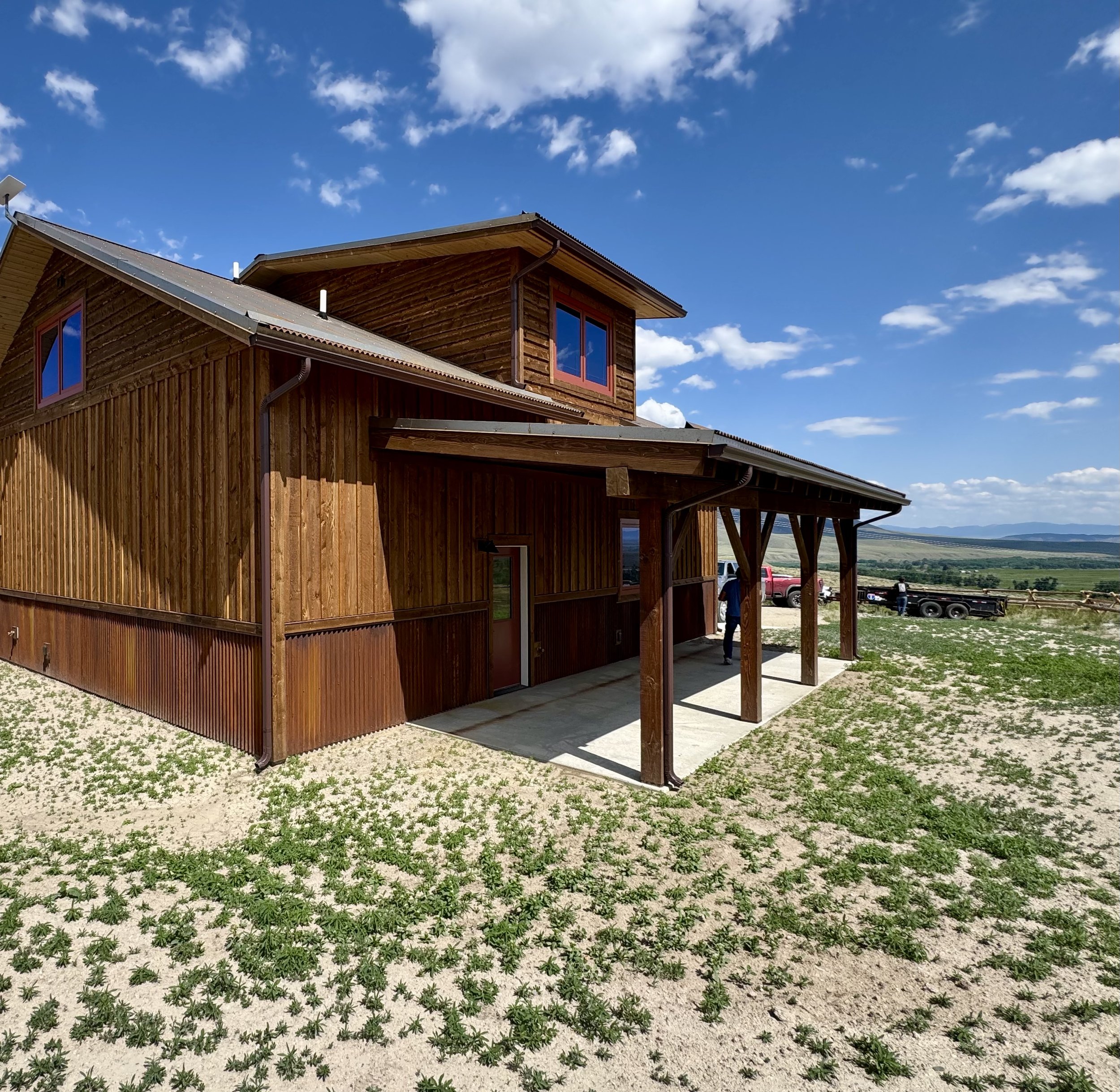 Custom rustic residence exterior with natural wood siding under Montana big sky — Mihelich Custom Builders, Glen, Montana.