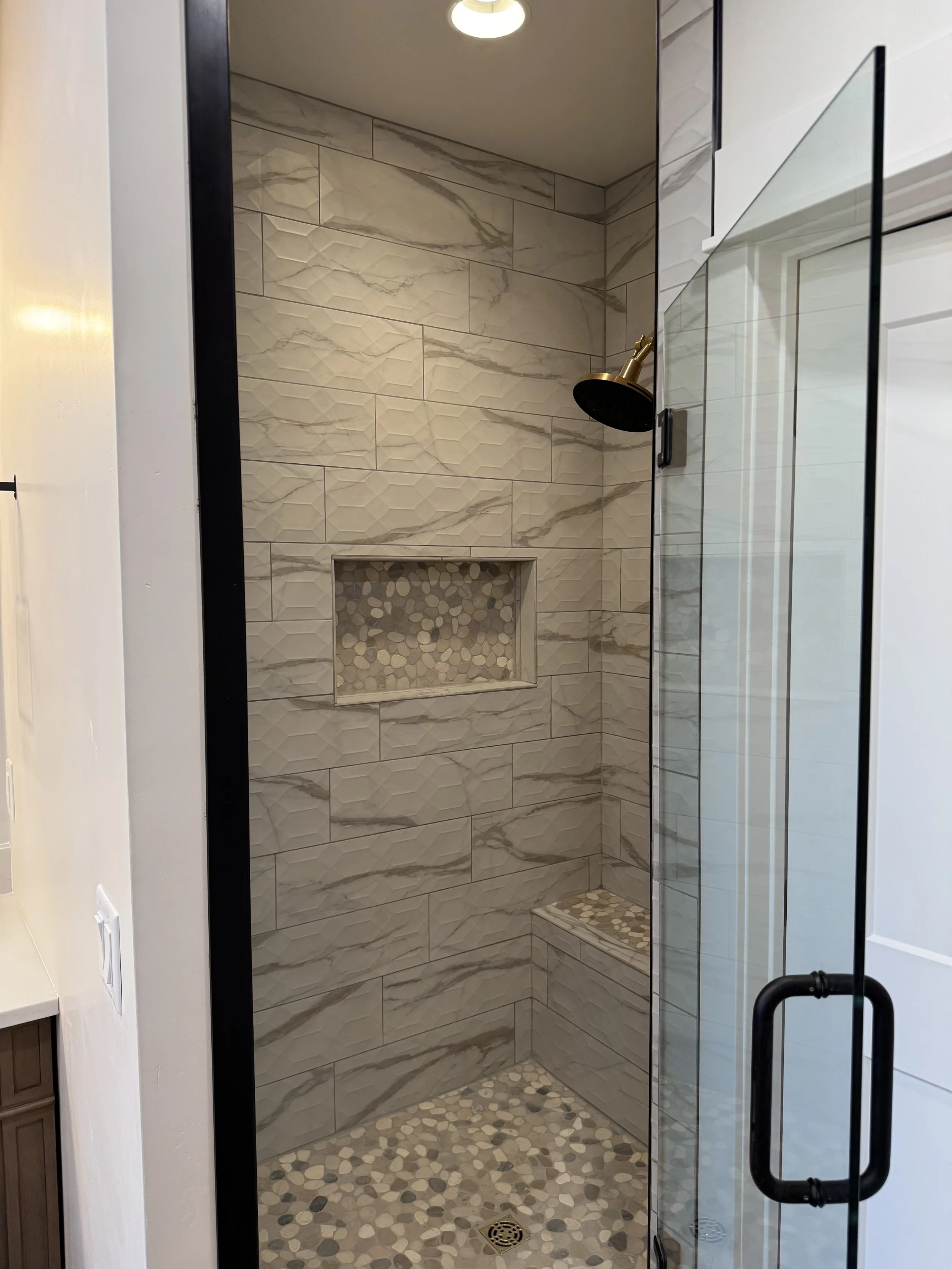 Custom walk-in shower with stone tile surround — luxury primary bathroom by Mihelich Custom Builders near Butte, Montana.