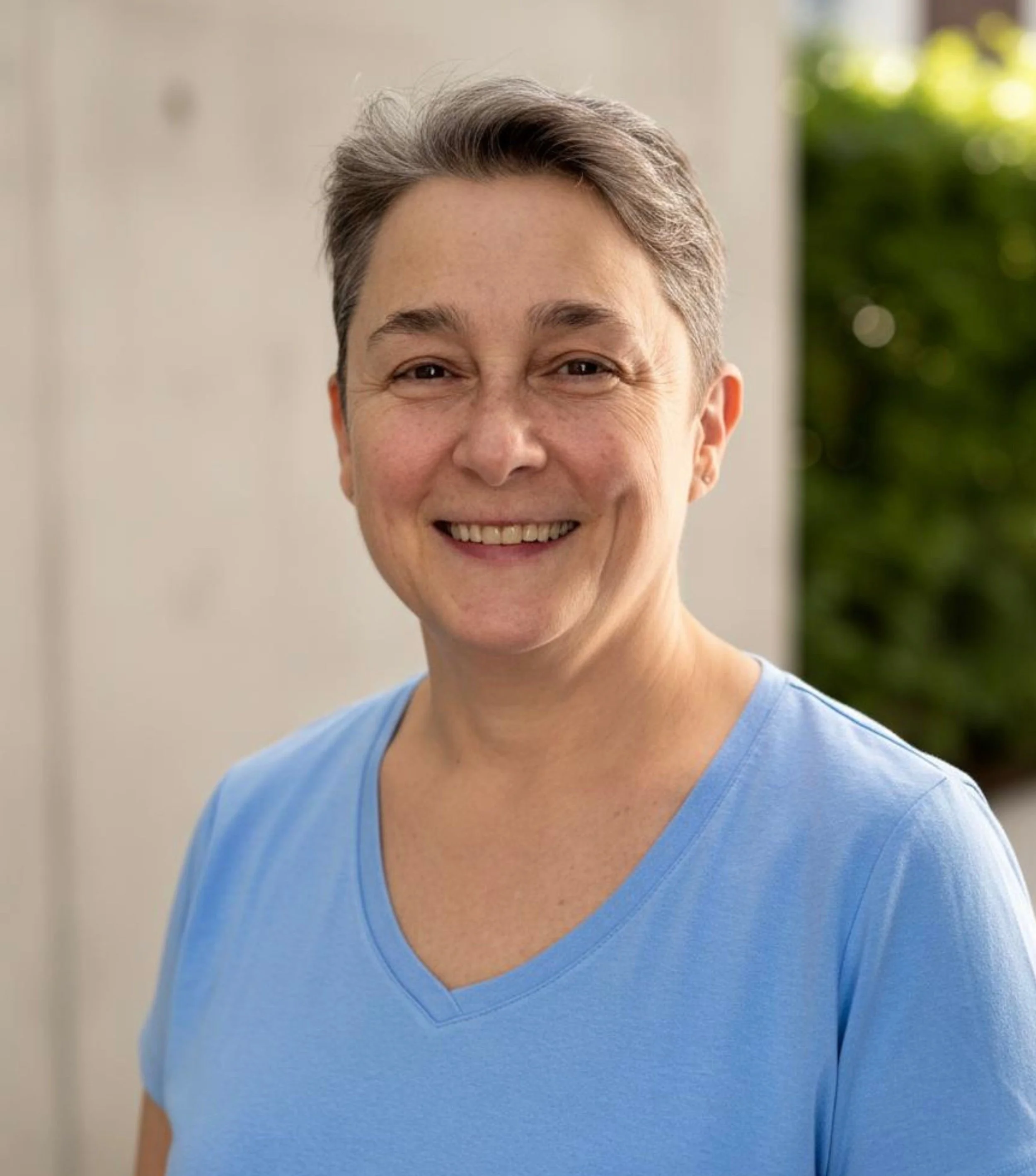 Portrait of Christine in a blue shirt, smiling.