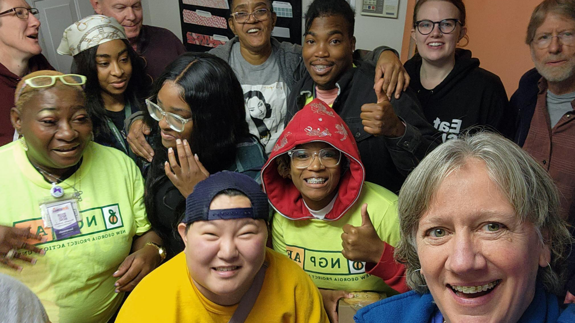 A diverse group of people smiling and gathering closely for a selfie, some wearing bright yellow t-shirts that read 'King County'.