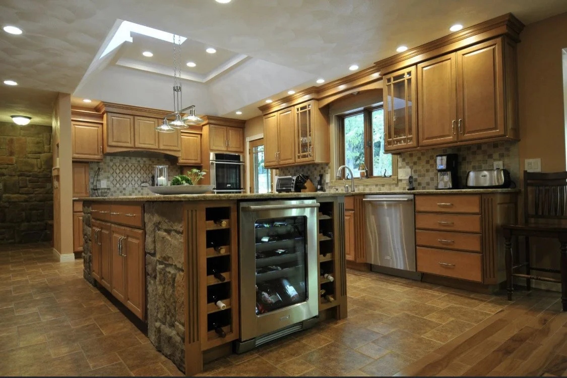 Kitchen with wooden cabinets, stone island, wine cooler, stainless steel appliances, and large windows.