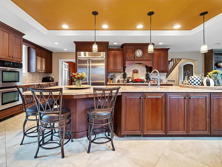 Modern kitchen with wooden cabinets, an island with barstools, stainless steel appliances, and pendant lighting.