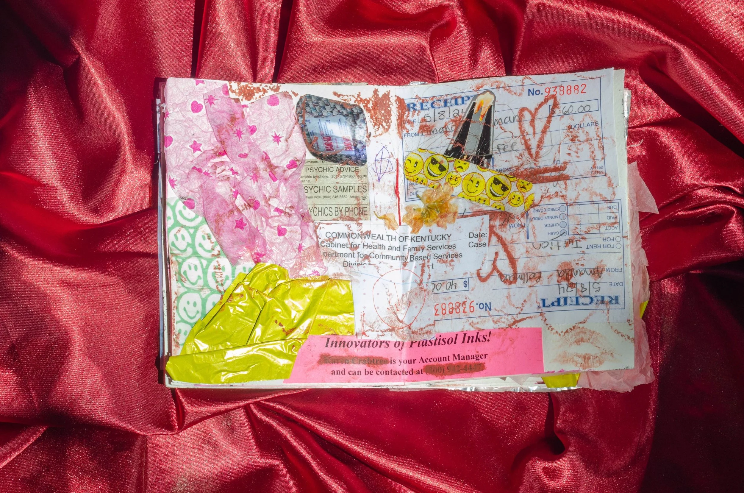 A mixed media collage on a red satin background, featuring a torn receipt, colorful stickers, pink and yellow tissue paper, and handwritten doodles.